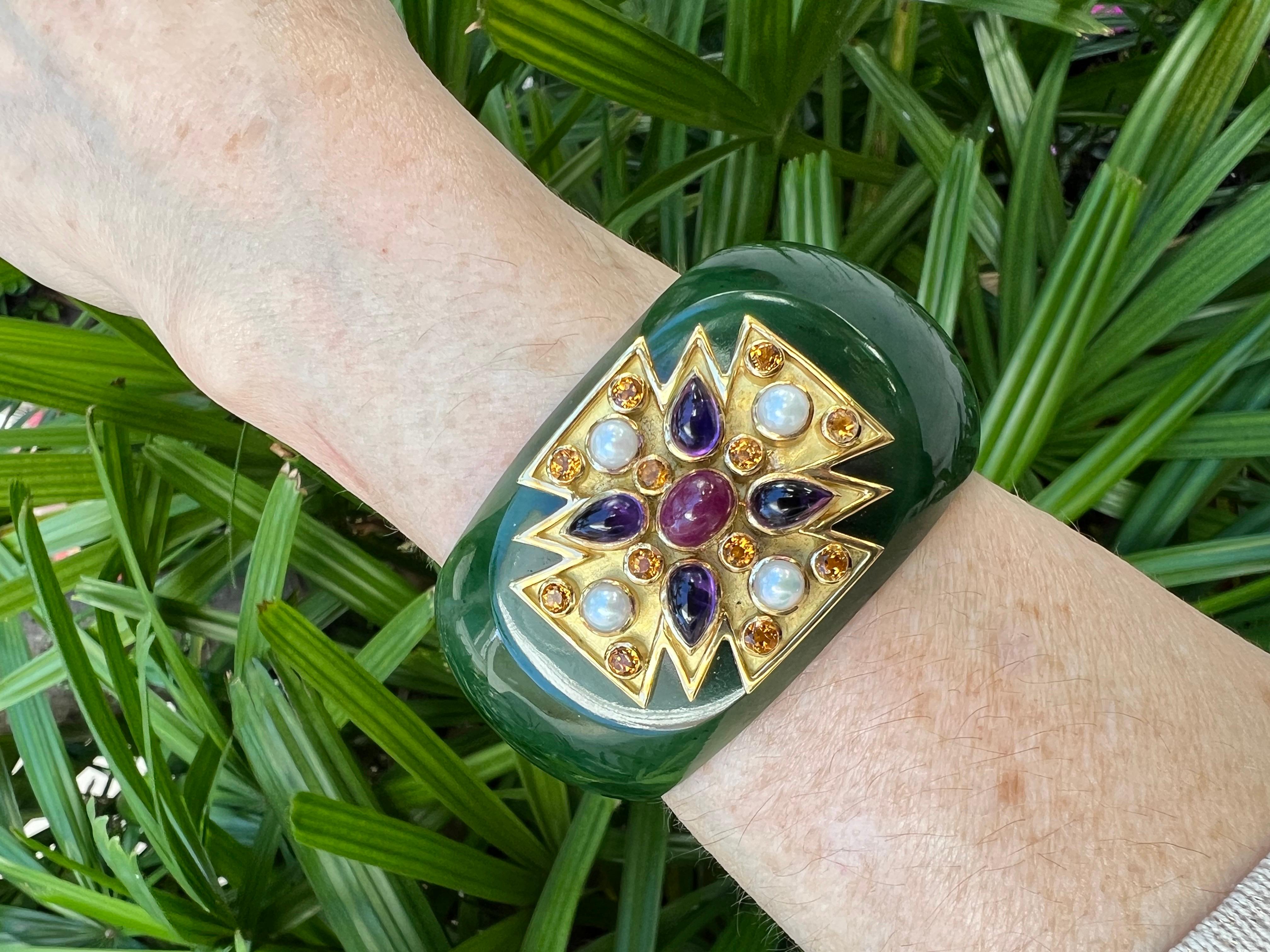 Verdura cuff bracelet, designed as a wide dark green jade cuff centering upon an 18k yellow gold Maltese Cross motif set with a larger oval cabochon-cut ruby at center surrounded by four pear cabochon-cut amethysts, as well as twelve round-cut
