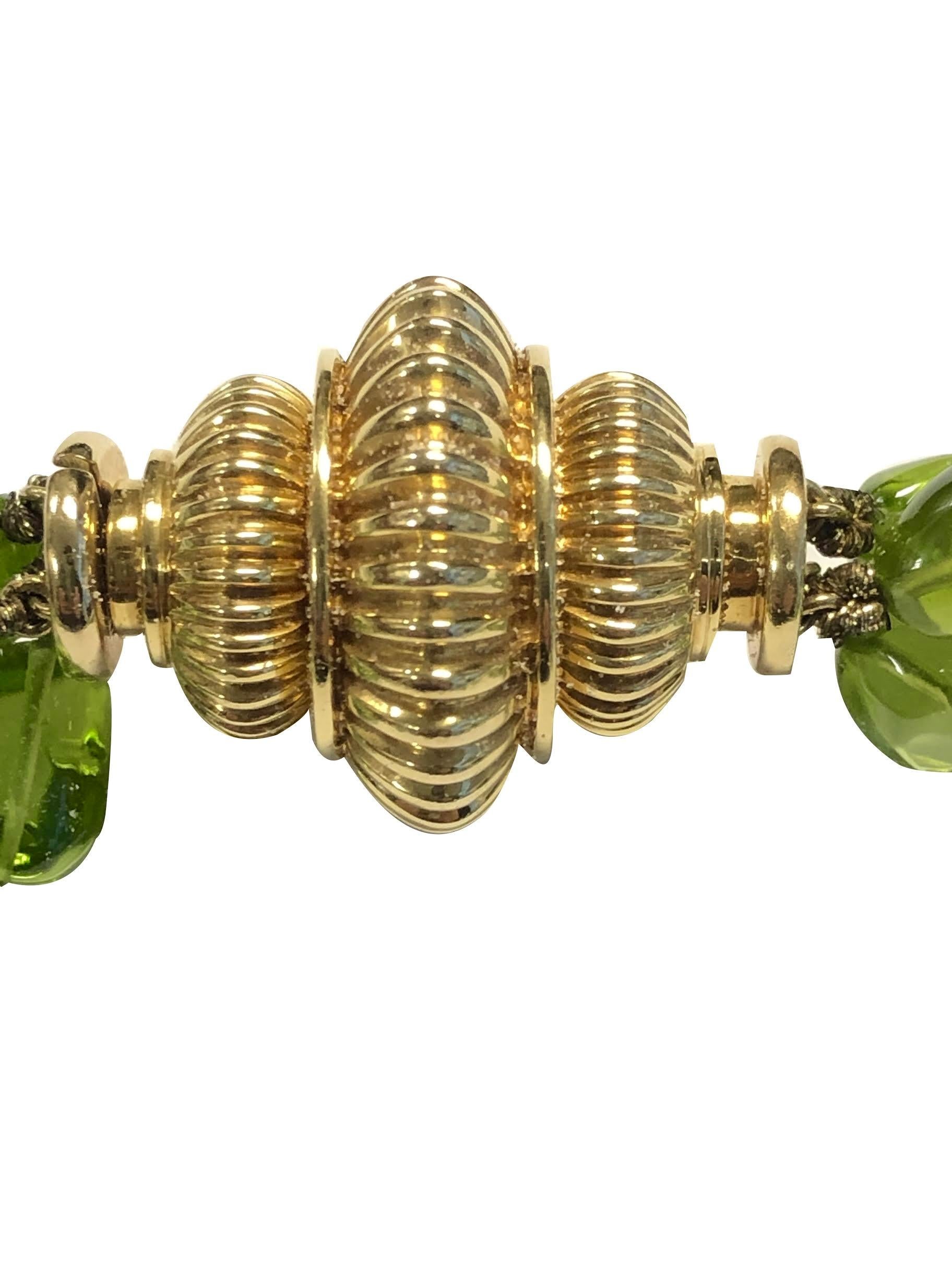 Circa 2000 Verdura Triple Strand Peridot Necklace, Gem color Polished Peridots measuring on the average 12 X 9 m.m. Each of the 3 strands varies in length with the longest being 32 inches. A large Fluted 18k Yellow Gold clasp measuring 1 1/4 X 1