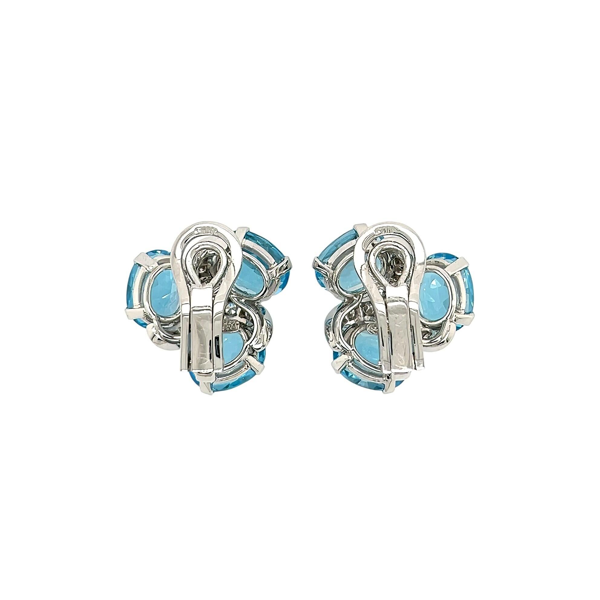 A pair of 18 karat white gold, blue topaz and diamond earclips, Verdura.  Each Three Stone earclip set with three oval faceted blue topazes around a central pinwheel motif set with nine round brilliant cut diamonds.  Total diamond weight