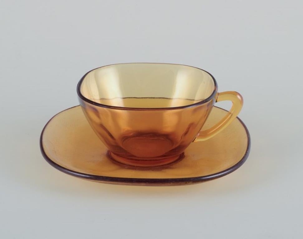 Vereco, France. Un ensemble de trois tasses à café avec soucoupes en verre ambré. 
Design/One.
Depuis les années 1970.
Marqué.
En bon état avec des signes d'utilisation.
Tasse : D 8,8 cm sans anse x H 4,5 cm.
Soucoupe : 13,4 cm.