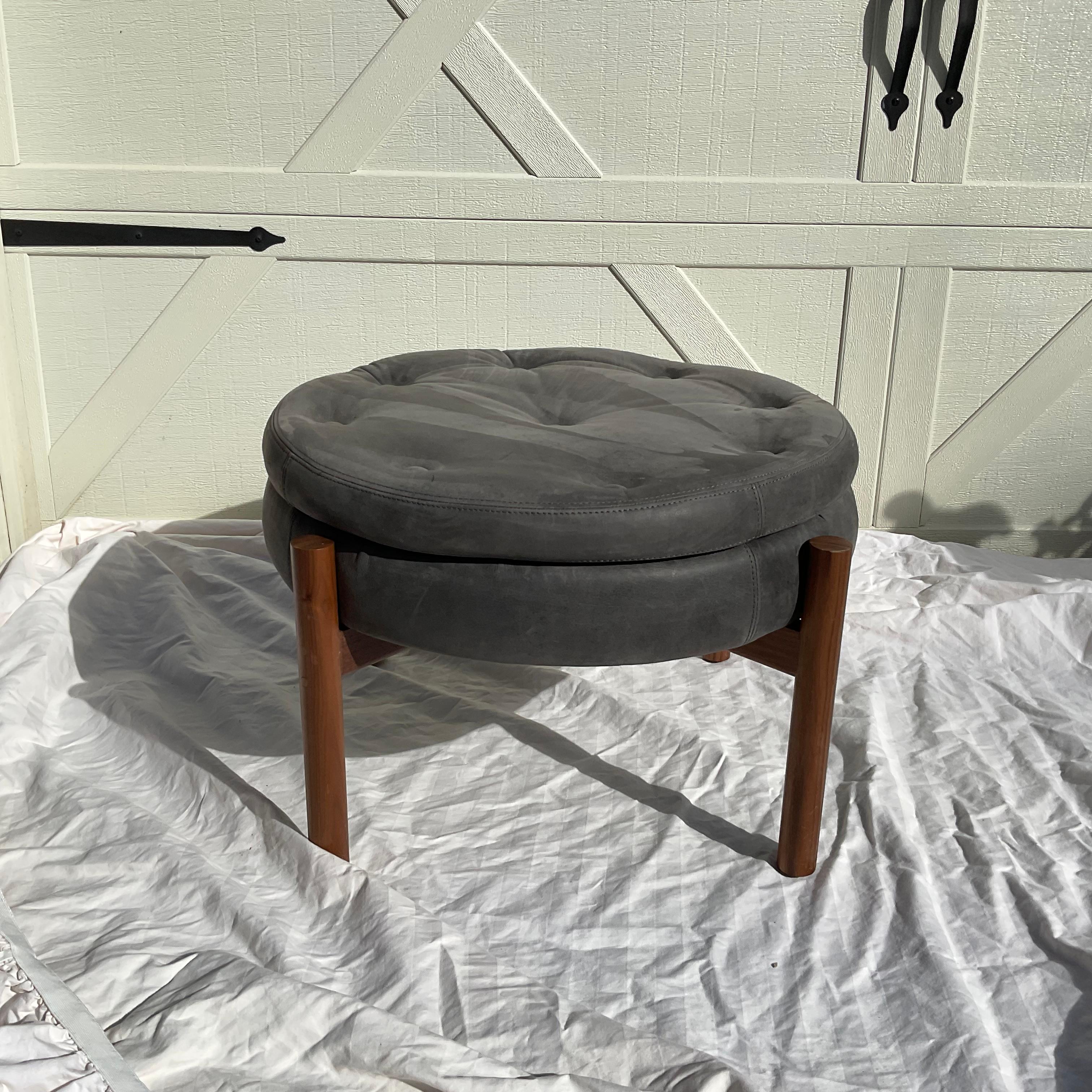 Very handsome, Danish Modern style round ottoman by Verellen, High Point, NC. The Hayes ottmoman, has a solid walnut X base frame with a tufted gray suede top. In very good estate condition, with only slight wear to the suede.