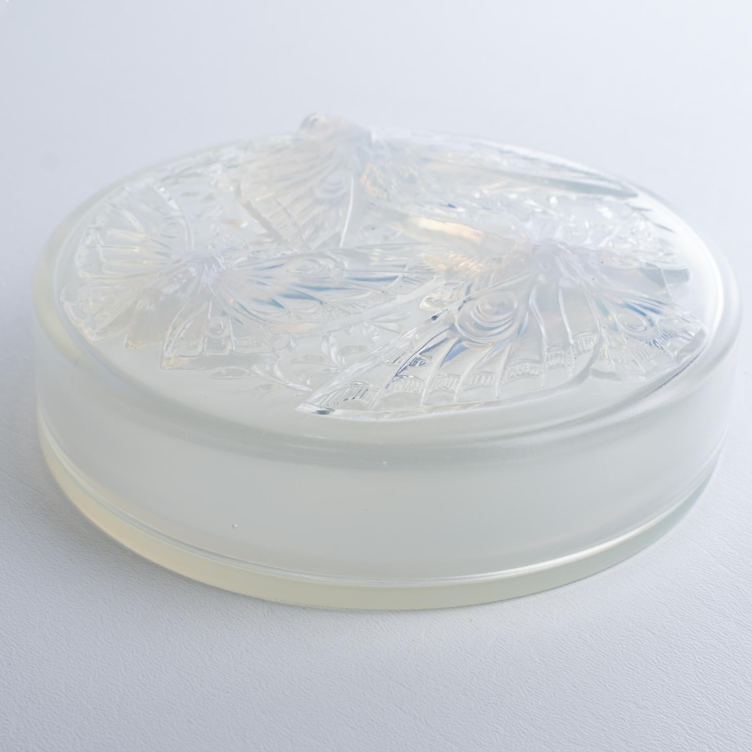 Verlys France diseñó esta exquisita caja con tapa Art Déco, que se fabricó en Francia hacia principios de 1930. Esta rara caja ostenta un asombroso diseño de textura azulada opalescente con una magnífica decoración moldeada en la tapa. La decoración