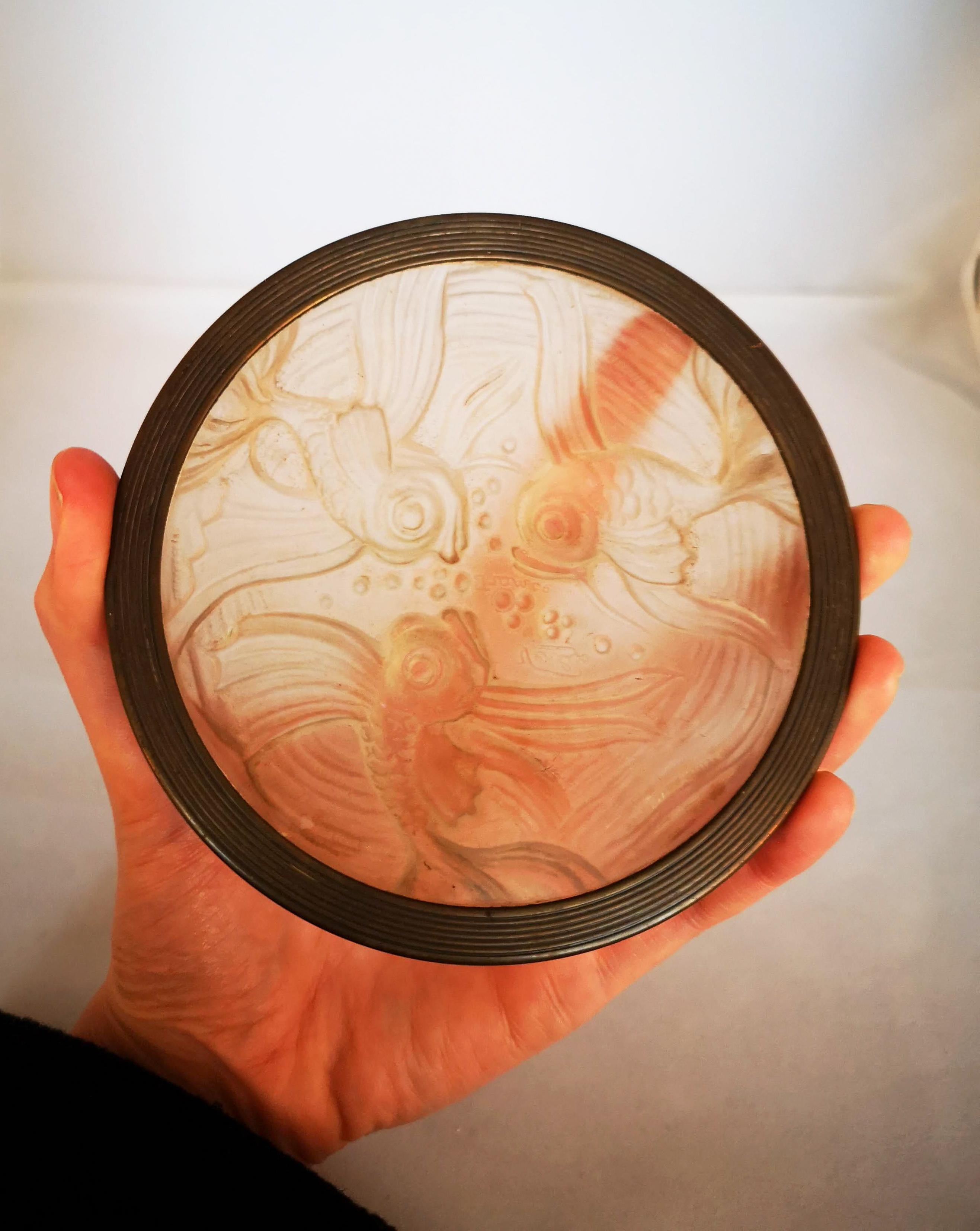 Un posavasos de vidrio opalescente Verlys de la Francia de los años 30, que muestra la elegancia del diseño Art Déco con un motivo de pez de estilo Lalique en relieve.

Esta pieza finamente elaborada, identificada como modelo 1455 en el catálogo