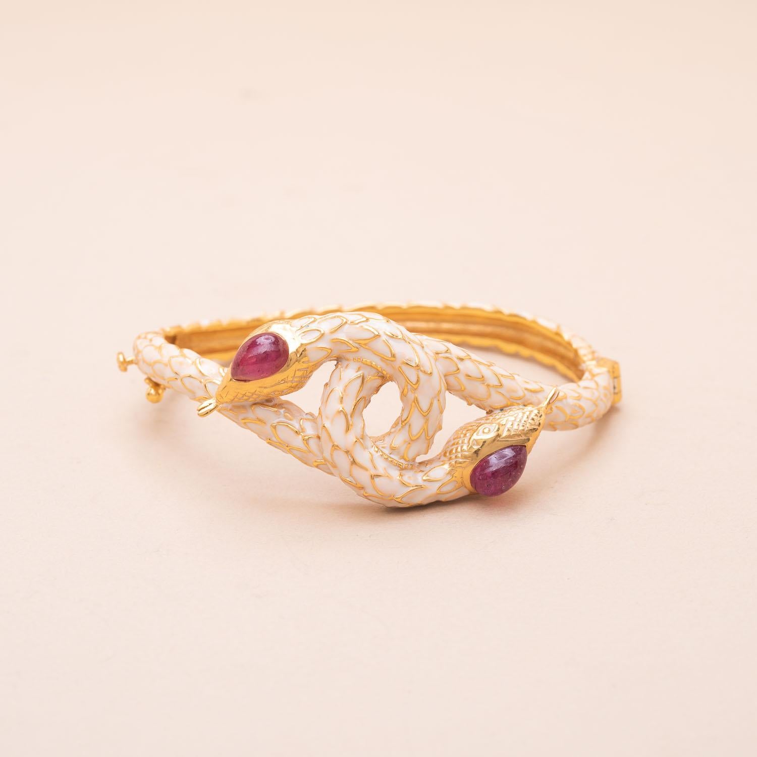 Vermeil bangle bracelet forming two cream enameled snakes 
Each snake's eye is made of cabochon-cut rubies 
Total weight of rubies : 2.5 carats 
Wrist size : 17cm 
Gross weight : 29.37g 

______________________

Bracelet jonc en vermeil (925°/00)