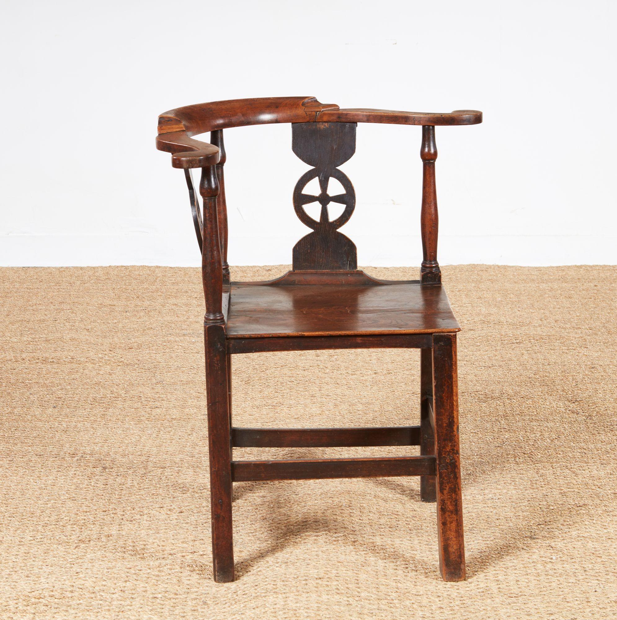 Charming early 19th century English country corner chair in elm, ash and fruitwood, the compass back with scrolled arms and shallow back crest over unusual 