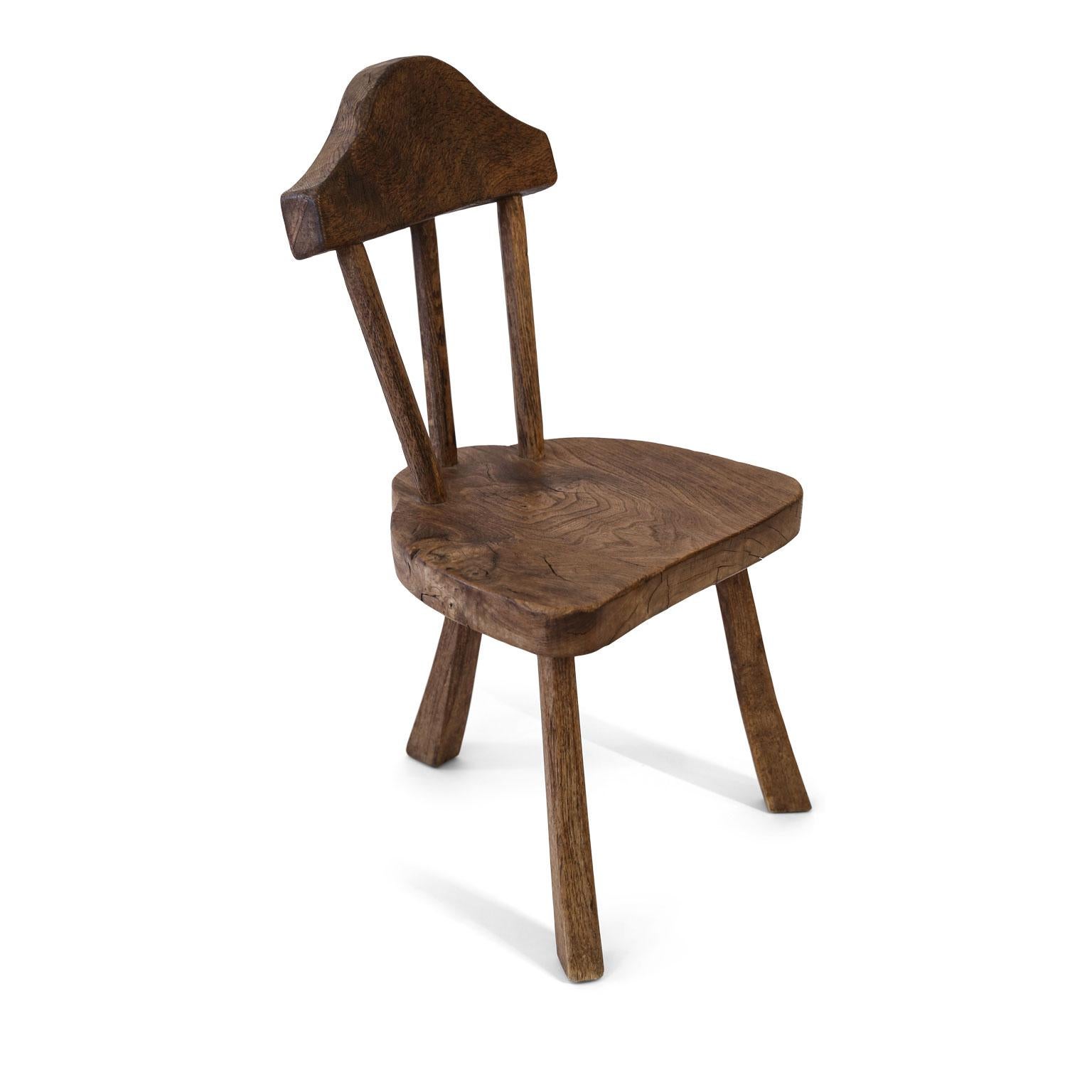 Stick back chair in mid-brown oak, constructed, circa 1925. This charming Folk Art chair in adzed oak comes from Norfolk, England, and is signed under its seat: 