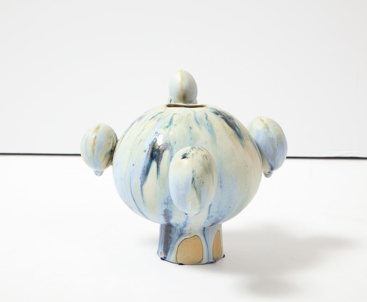 Glasiertes Porzellan.  Kugelförmige Vase mit Fuß und aufgesetzten runden Formen. Blaue und grüne Glasuren.  Auf der Unterseite vom Künstler signiert.