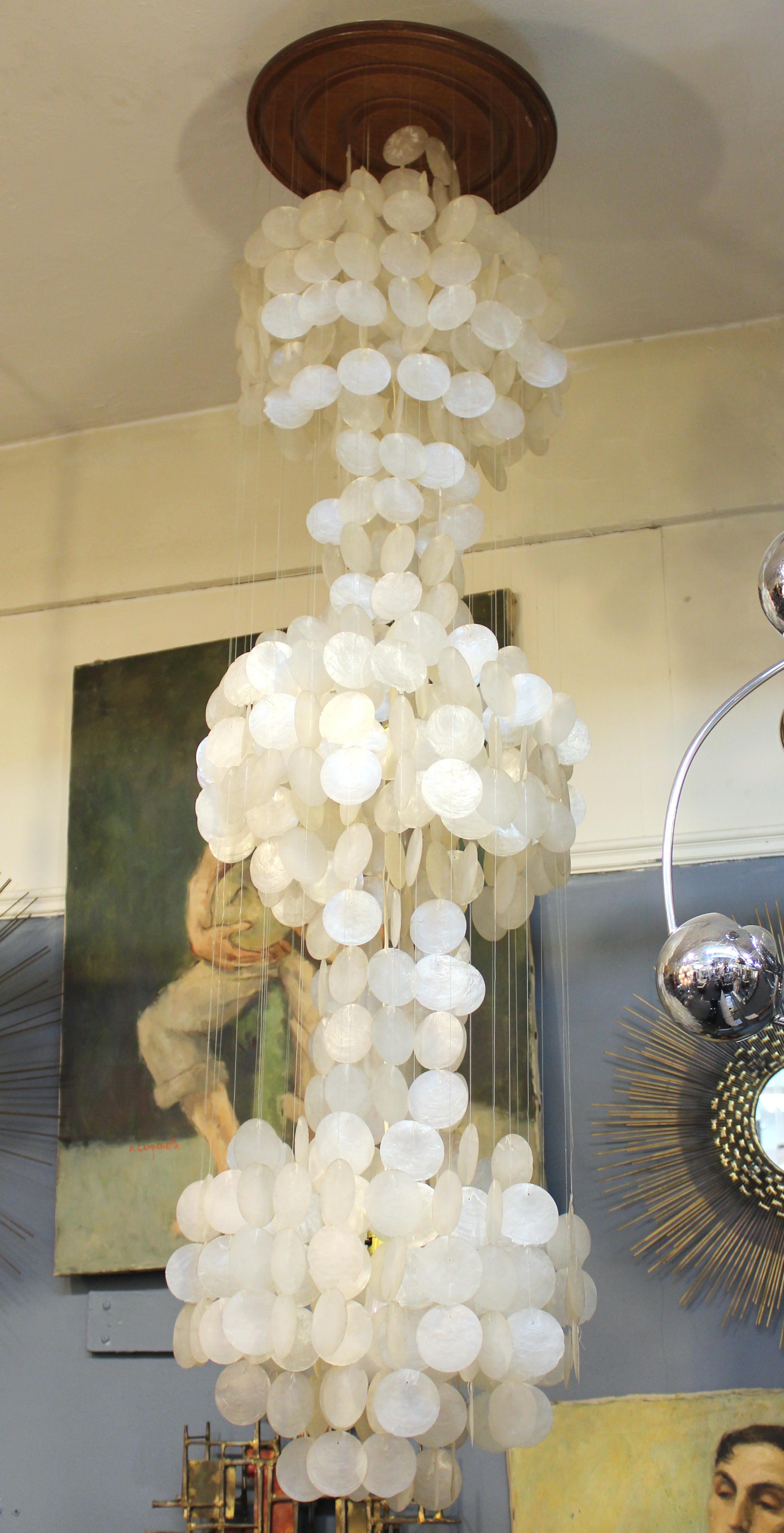 Mid-Century Modern monumental capiz shell chandelier, made by Verner Panton in the 1960s. The piece has a wooden mount piece and three levels of spheres shaped by hanging capiz shell discs. In great vintage condition.