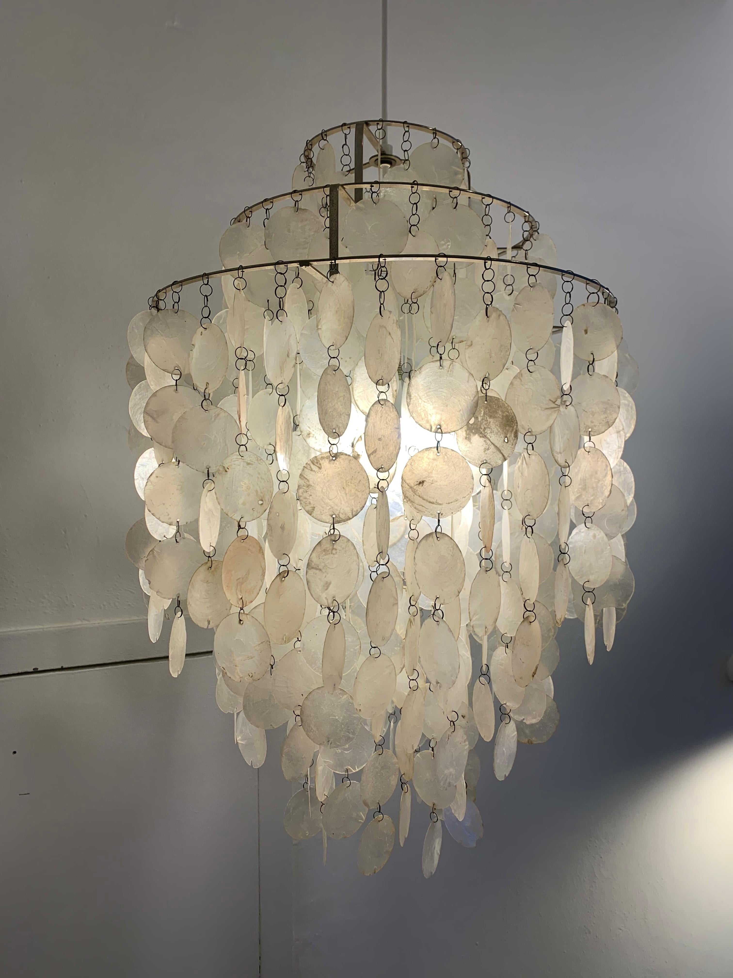 Mother-of-pearl Fun 1DM pendant designed by the Danish designer Verner Panton in 1964, part of a series of luminaires under the name 'Fun'.
Base structure of steel on which chains with mother-of-pearl discs are mounted. When the wind catches the