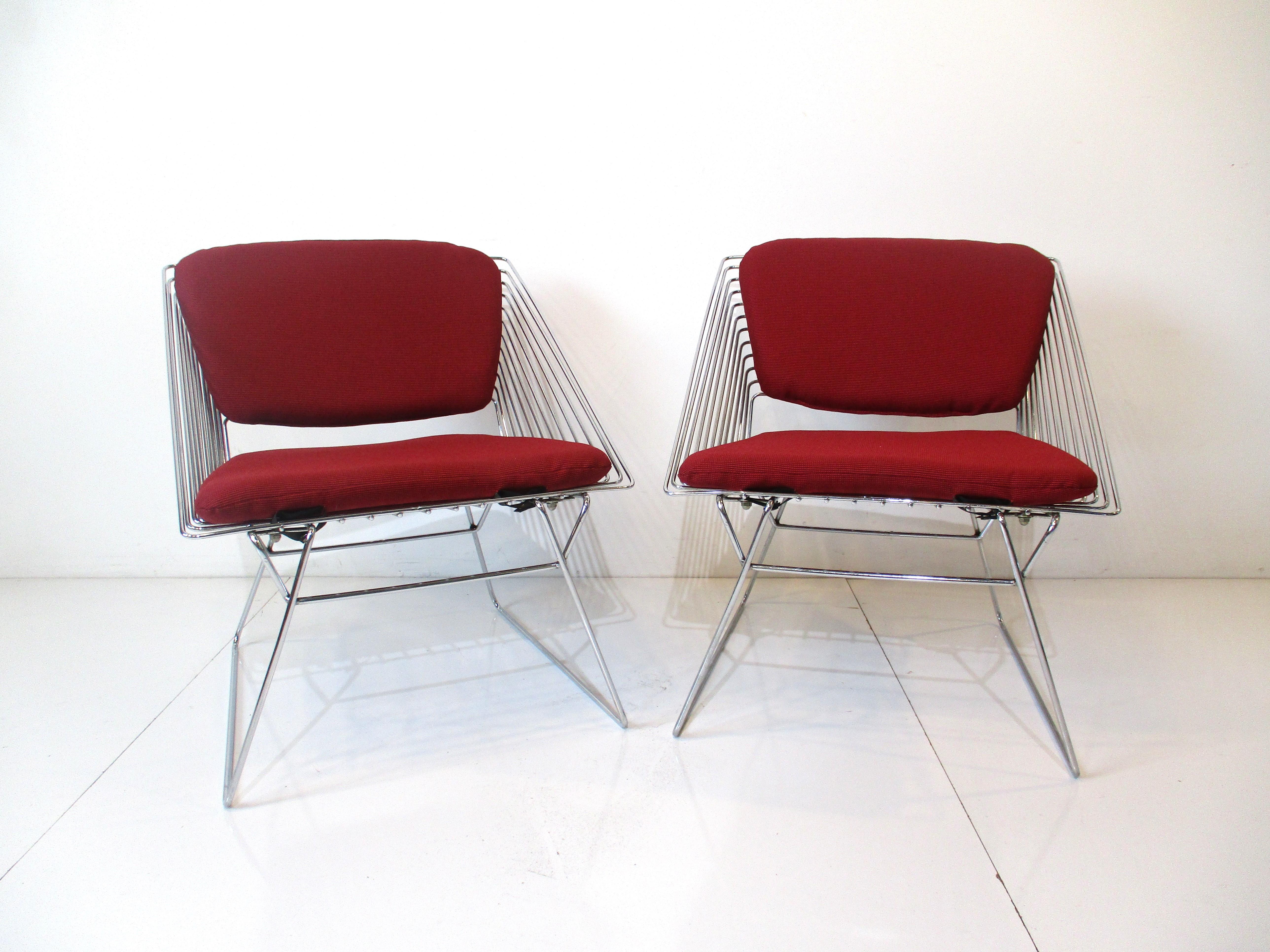 A pair of chromed metal wire grid chairs with snap on upholstered back and bottom cushions. These geometric cube styled lounge chairs are comfortable and have that lighter modern 1970's look with the new woven darker reddish contract fabric sourced