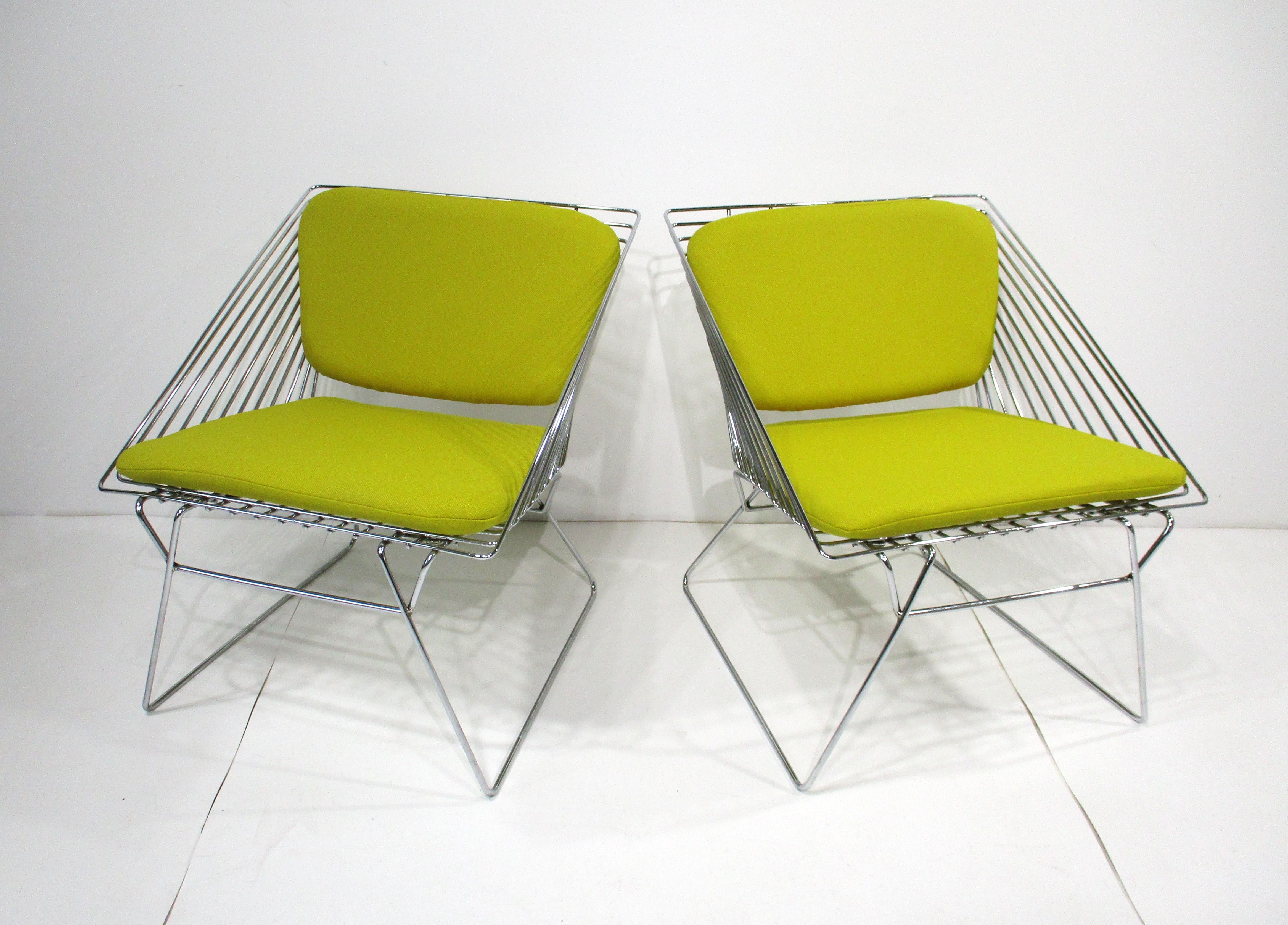 A pair of chromed metal wire grid chairs with snap on upholstered back and bottom cushions. These geometric cube styled lounge chairs are comfortable and have that lighter modern 1970's look with the new woven yellow contract fabric sourced from