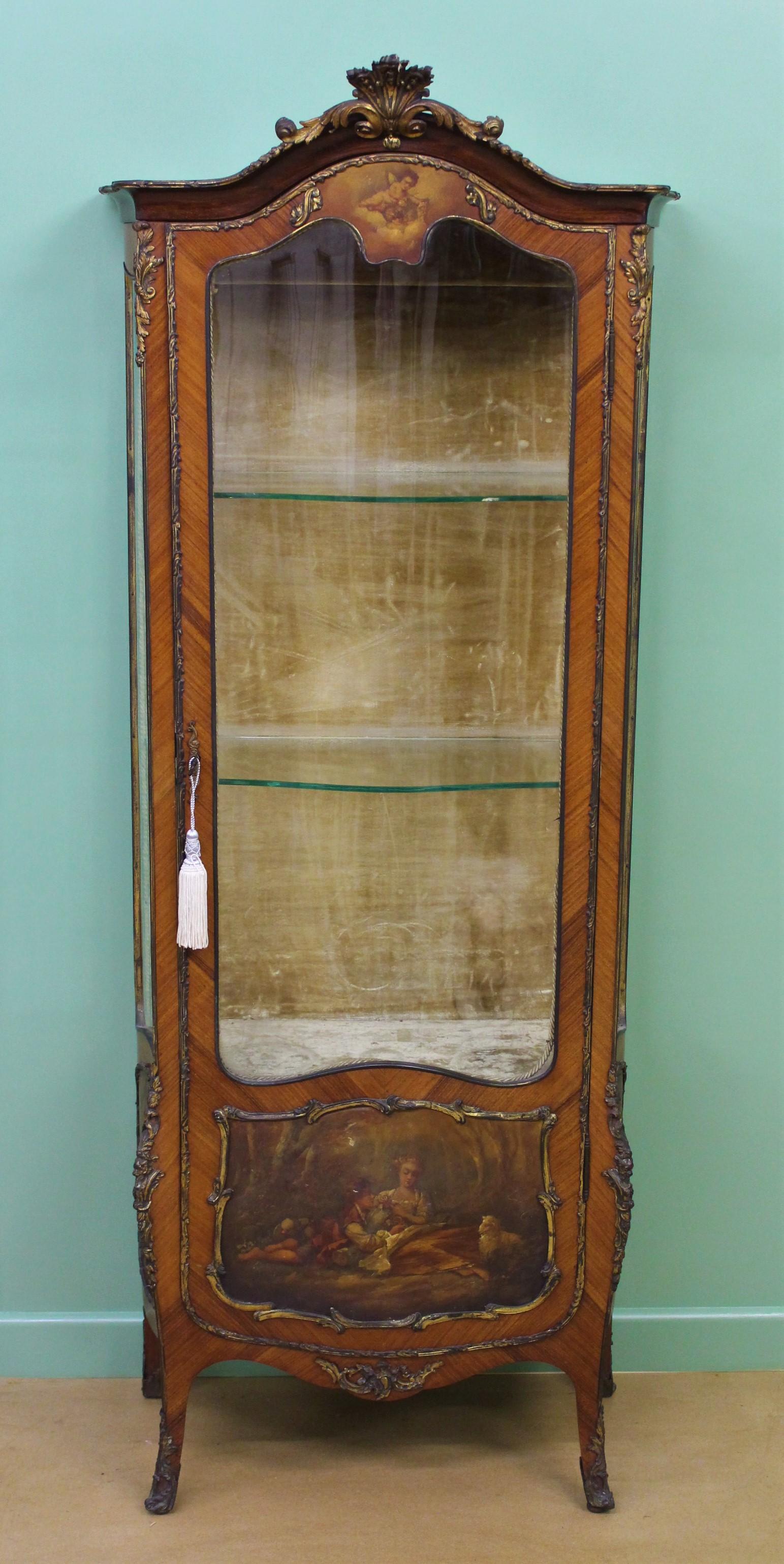 A charming and decorative French Kingwood vitrine. Decorated with lovely hand painted classical scenes and further embellished with crisply cast brass mounts. Of serpentine form and with a single door (lockable with key supplied) which opens to