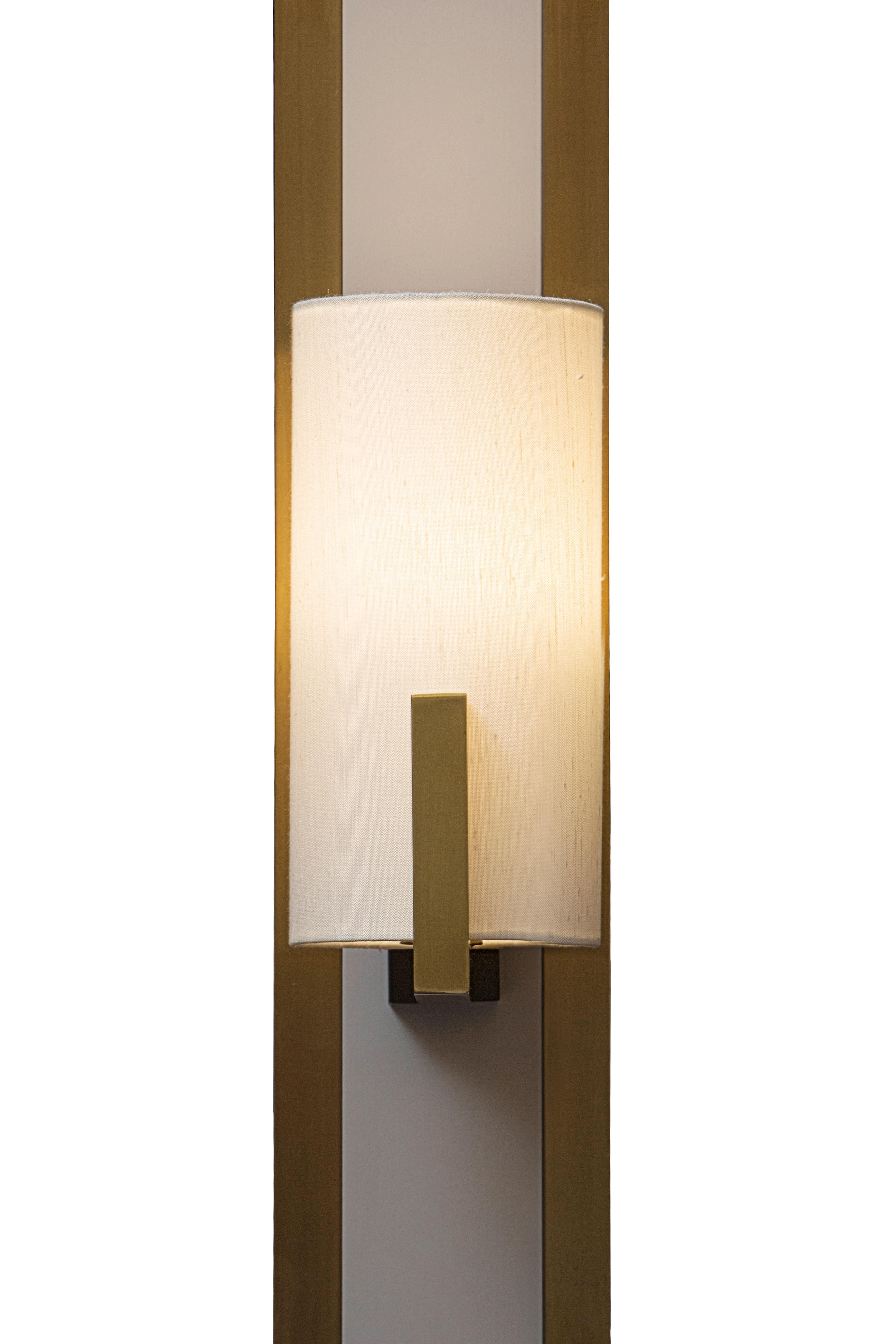The linear design of this elegant sconce is inspired by the nostalgic and romance-filled Los Angeles of the 1930s, with its Cafe Society atmosphere. The sophisticated silhouette of the piece is made of a brass structure covered with shantung silk