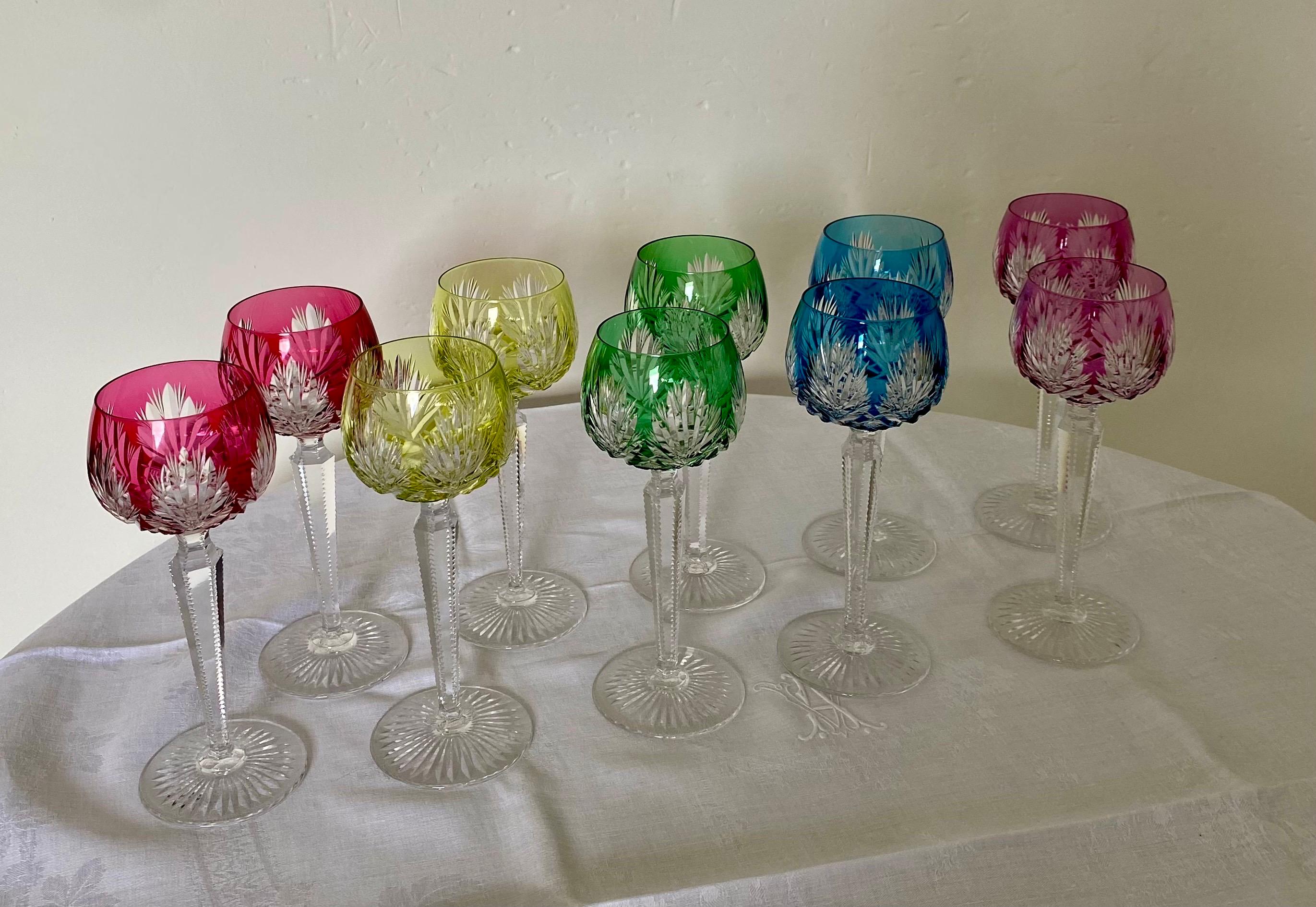 Série de dix verres à vin en cristal de maison française Saint-Louis. Ce modèle a été créé au milieu du XXème siècle. 
Ces verres en cristal taillé ont des jambages finement ciselé. 
Nous proposons ici cinq couleurs lumineuses. 
Tous les verres sont
