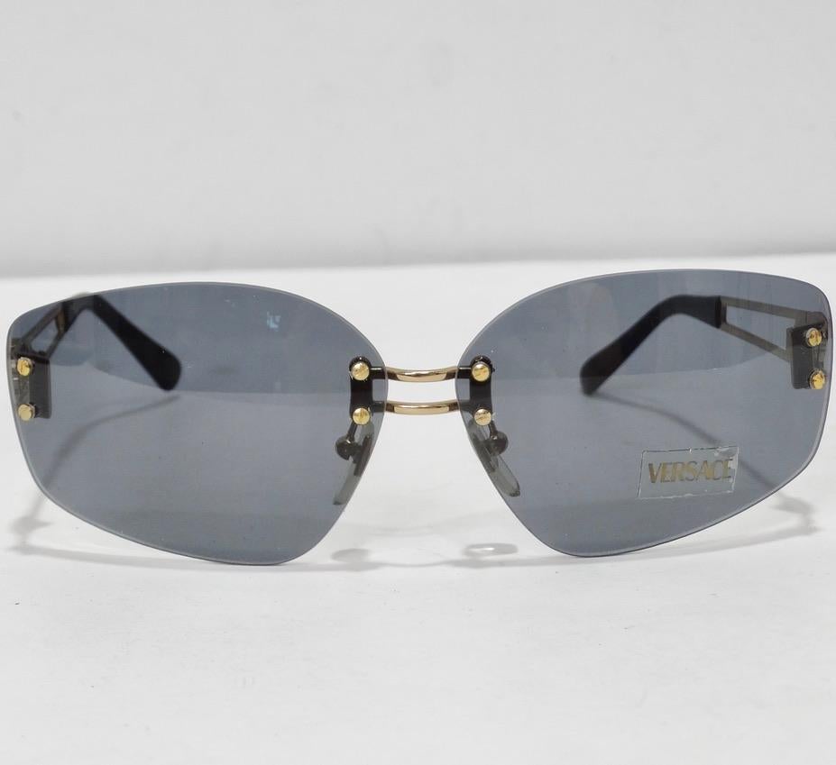 Ces lunettes de soleil de Versace, datant des années 1990, sont vraiment superbes ! Ces lunettes de soleil parfaites pour tous les jours sont dotées de verres gris bleus verdâtres et de détails noirs avec des accents dorés. Remarquez le motif de la