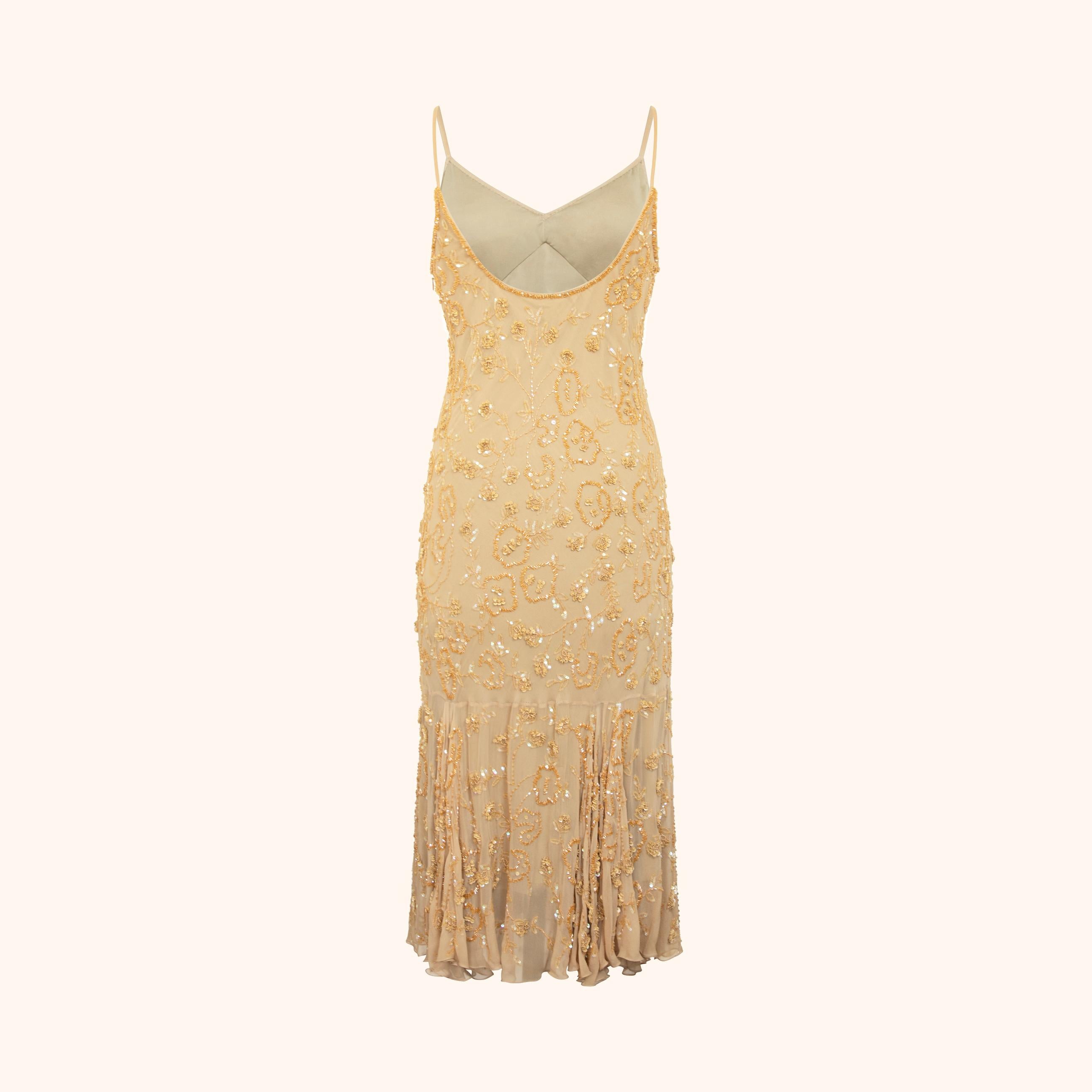 Transparente, nudefarbene Seide, die mit floralen Pailletten, Perlen und Fäden in goldenen und schillernden Tönen bestickt ist. 
Mit feinen Spaghetti-Trägern, strukturierten Cups und einem sanft ausgestellten Saum, der durch zarte Falten veredelt