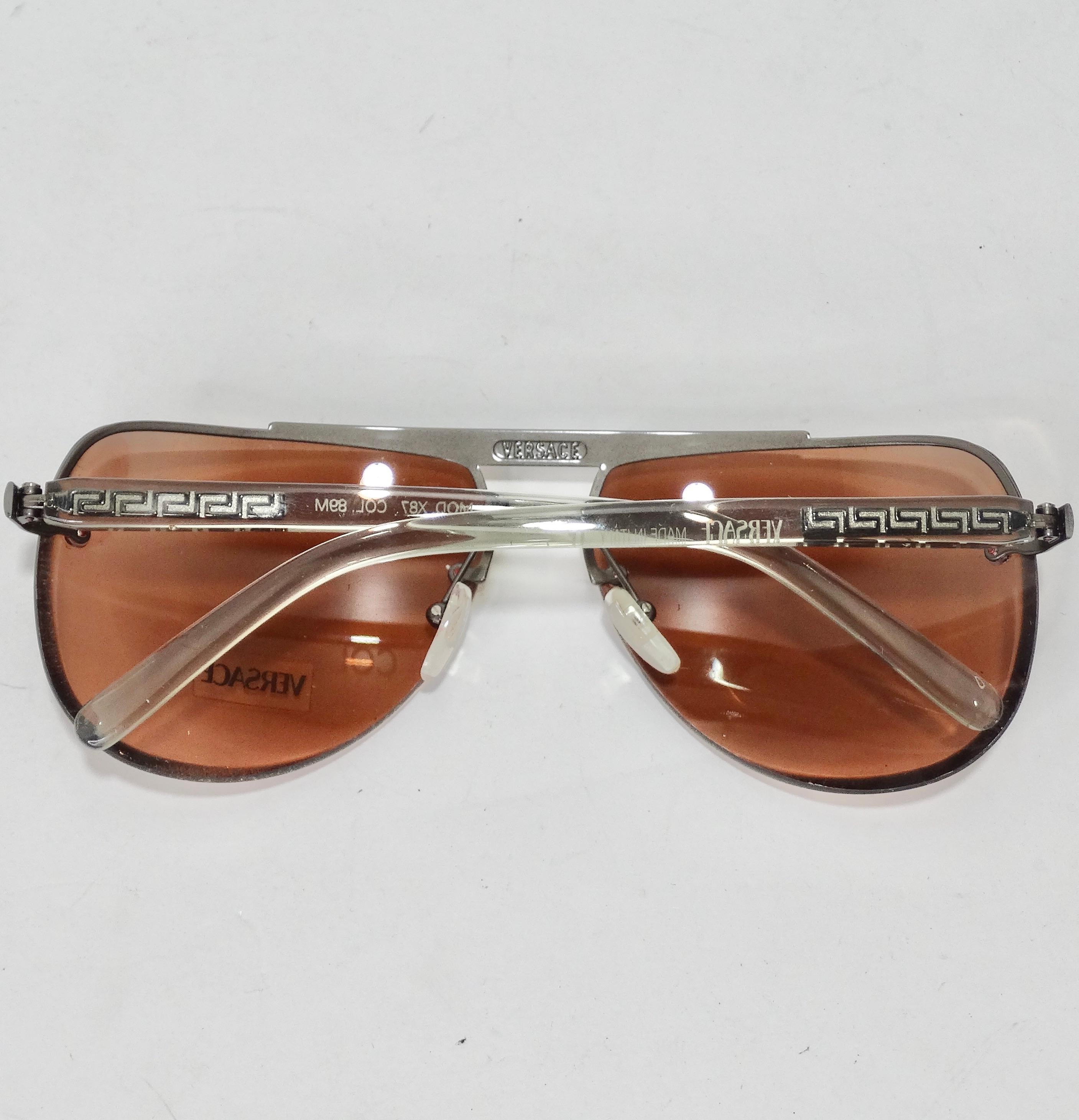 Mettez la main sur ces incroyables lunettes de soleil de Versace, datant des années 1990 ! Les lunettes de soleil parfaites de style aviateur sont dotées de verres roses poussiéreux et de détails argentés. C'est une paire de lunettes de soleil