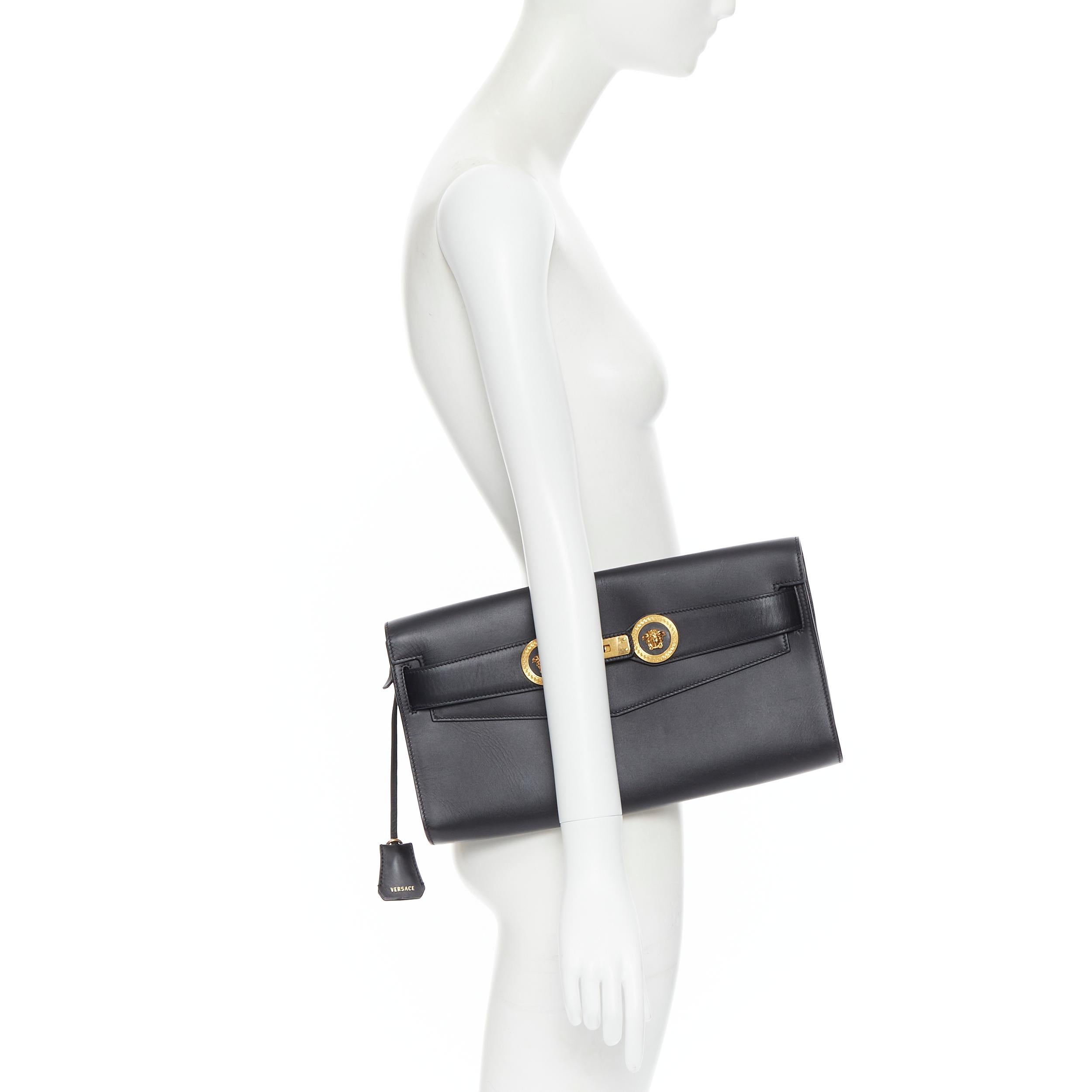 VERSACE 2018 Tribute Icon black gold Double Medusa coin Kelly clutch bag 
Reference: TGAS/B00588 
Brand: Versace 
Designer: Donatella Versace 
Model: Tribute Icon 
Material: Leather 
Color: Black 
Closure: Turnlock 
Extra Detail: Double Medusa Coin.