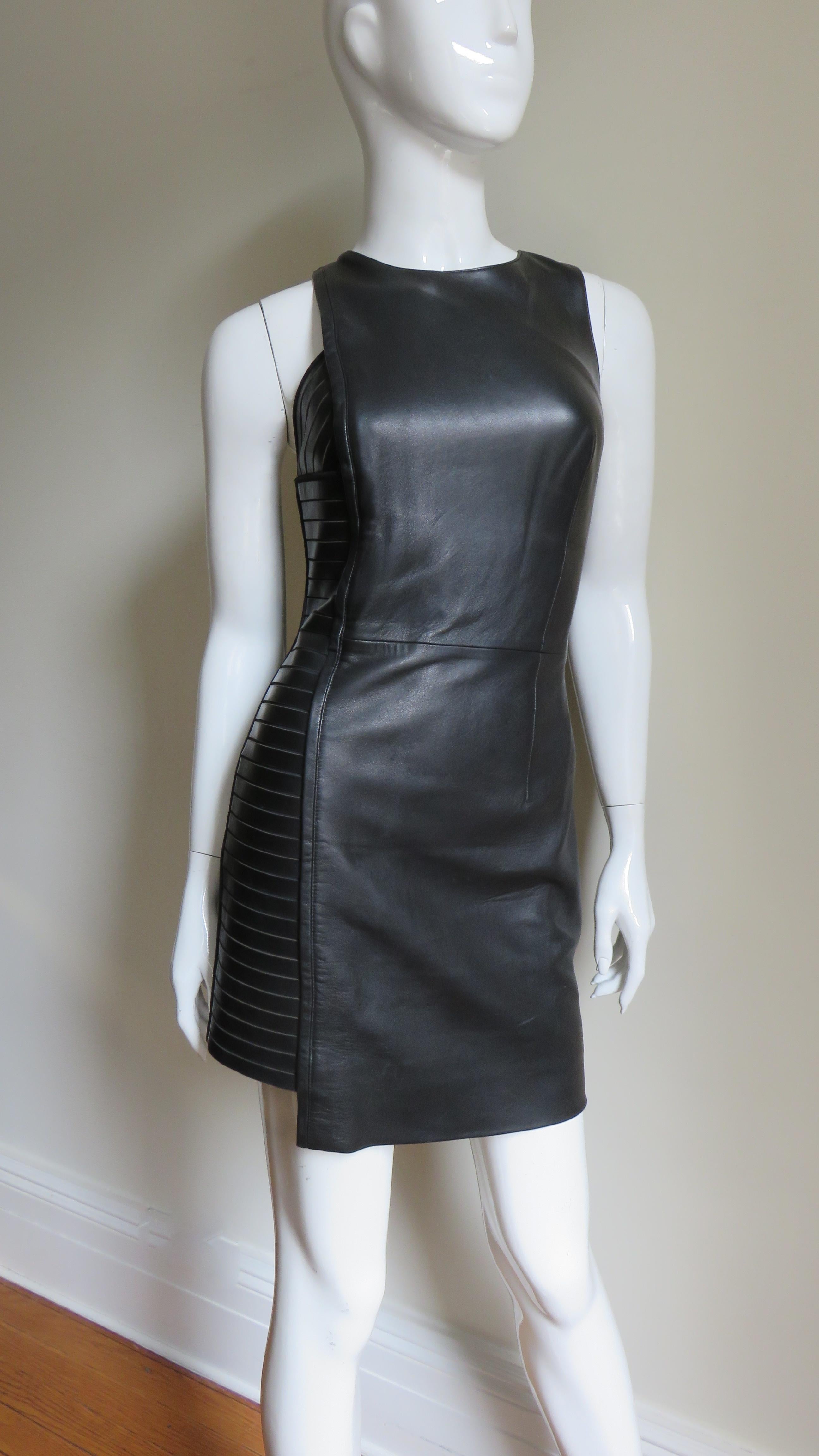 A fabulous black leather dress from Versace. It is sleeveless, semi fitted with a side panel of horizontal leather bands. The dress is fully lined with an invisible side zipper and hooks at one shoulder.
Fits size Extra Small, Small.  Marked size 40