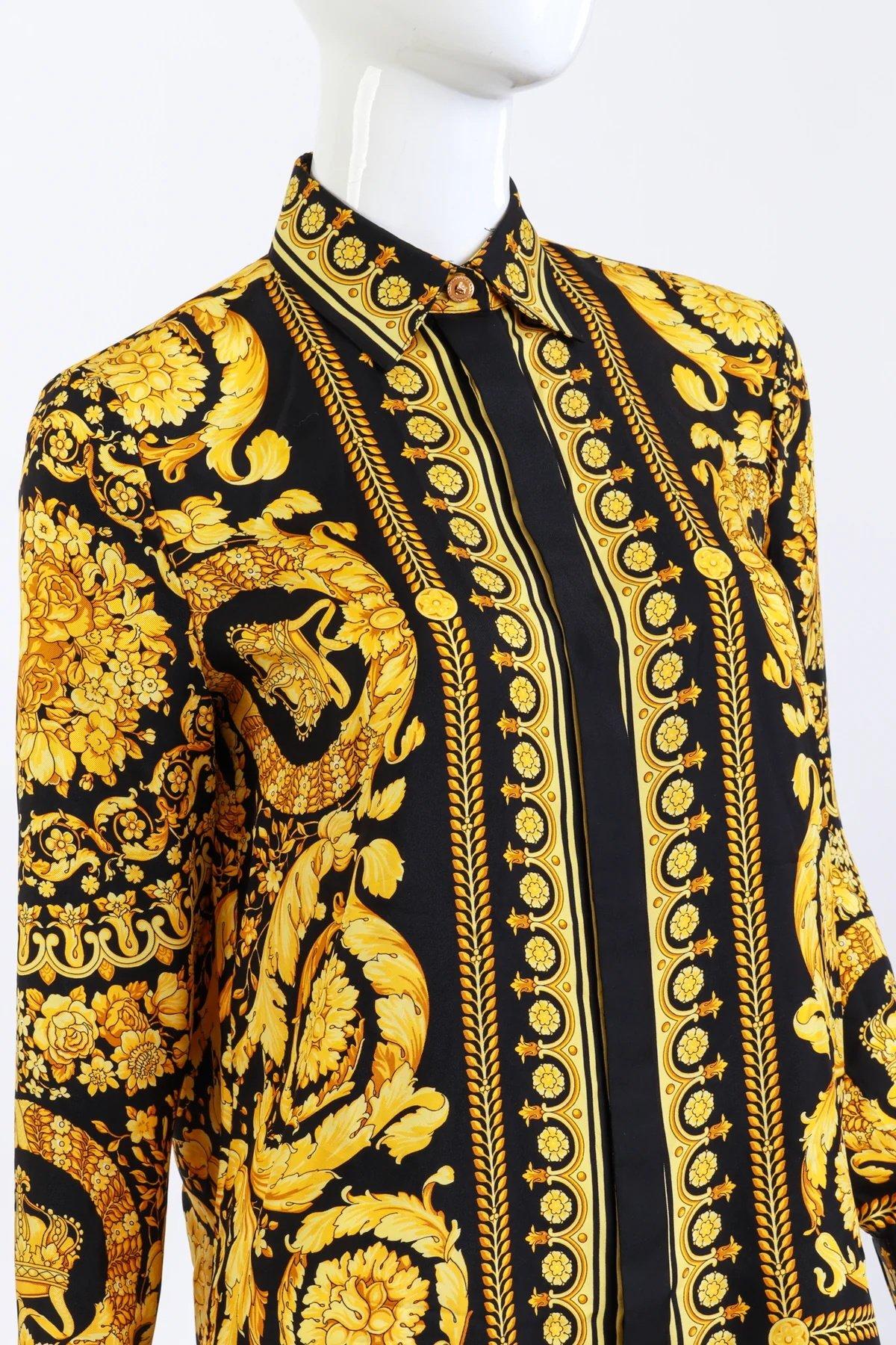 VERSACE BAROQUE CROWN SILK BUTTON UP SHIRT BLACK GOLD (S/M)

This Versace baroque silk button-up shirt features an opulent golden print on black silk, showcasing intricate crowns, scrolling acanthus leaves, and floral details. The design is framed