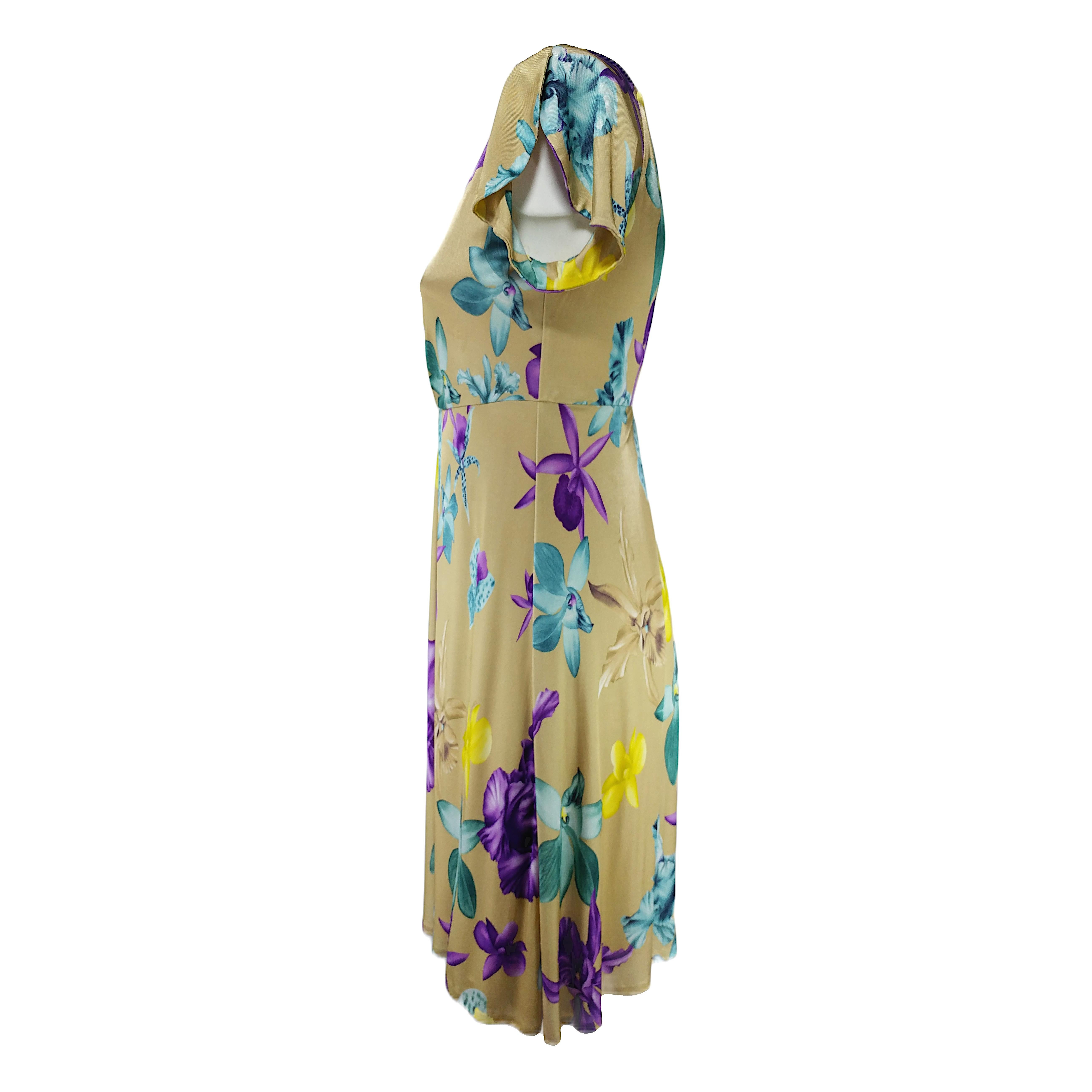 A glamorous vintage dress by Versace from the late 90s or early y2k, in excellent vintage conditions and carefully reconditioned. It features a wide round neckline, short sleeves and a soft viscose beige fabric printed with yellow, purple and green