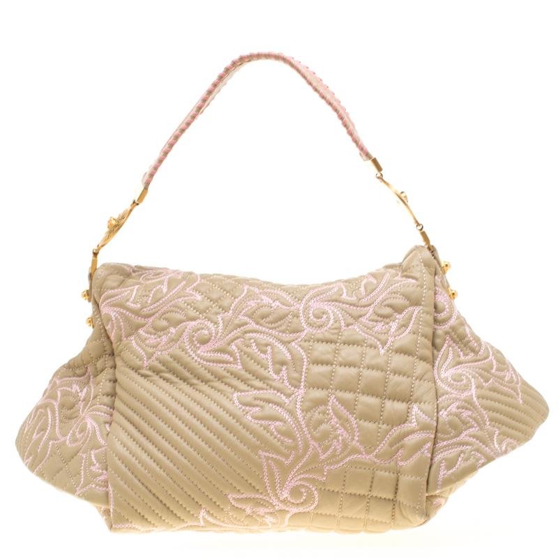 This Versace handbag is meticulously crafted from quilted leather. The Barocco bag delights not only with its appeal but structure as well. It is held by a single handle, adorned with a lovely embroidery all over and equipped with a spacious canvas