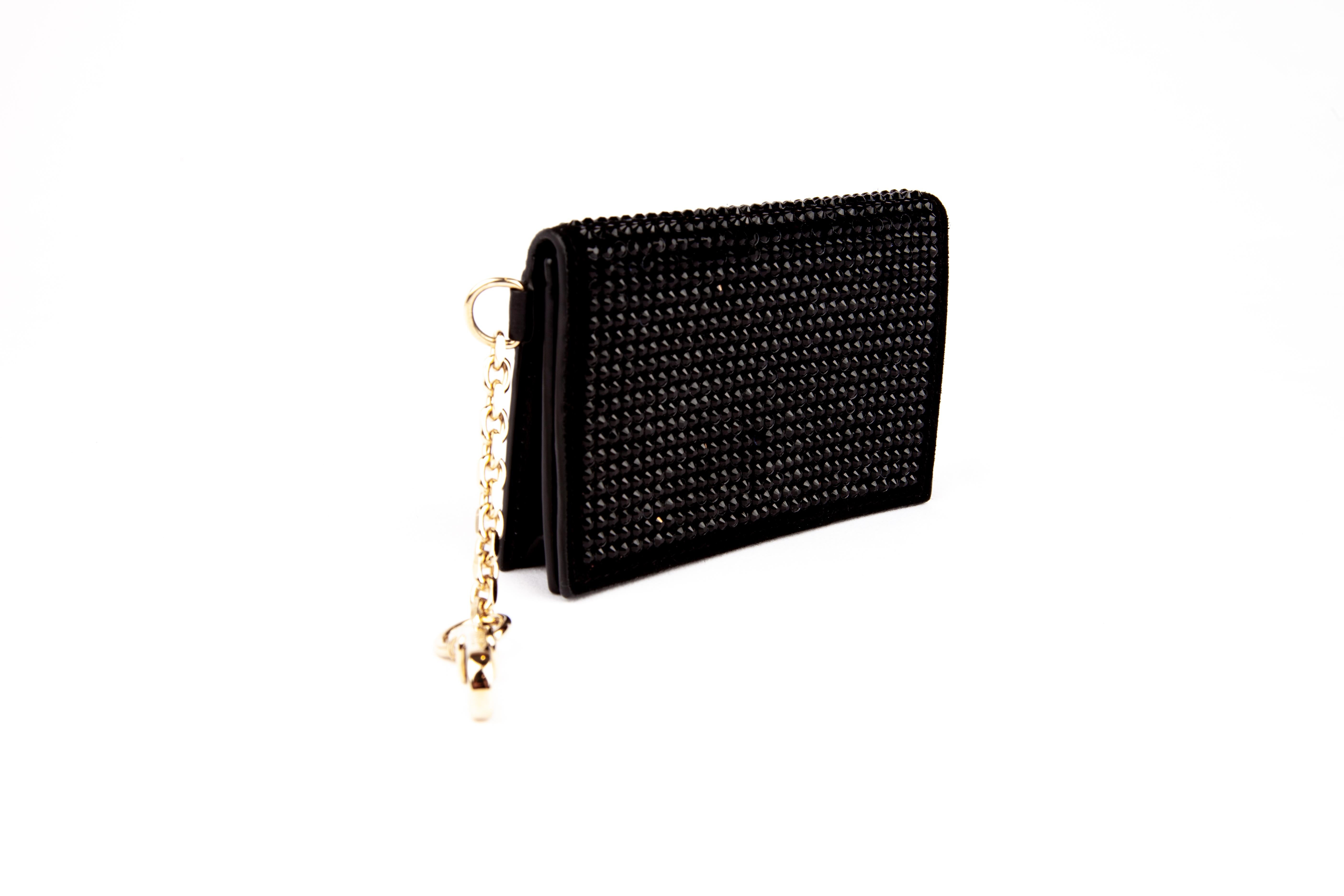 This Versace mini wallet / bag charm features black crystal embellishments, black suede and smooth leather, a snap fastening, two inside pockets, and gold tone hardware. It can be used as a card holder or can hook onto a handbag as as cute and fun