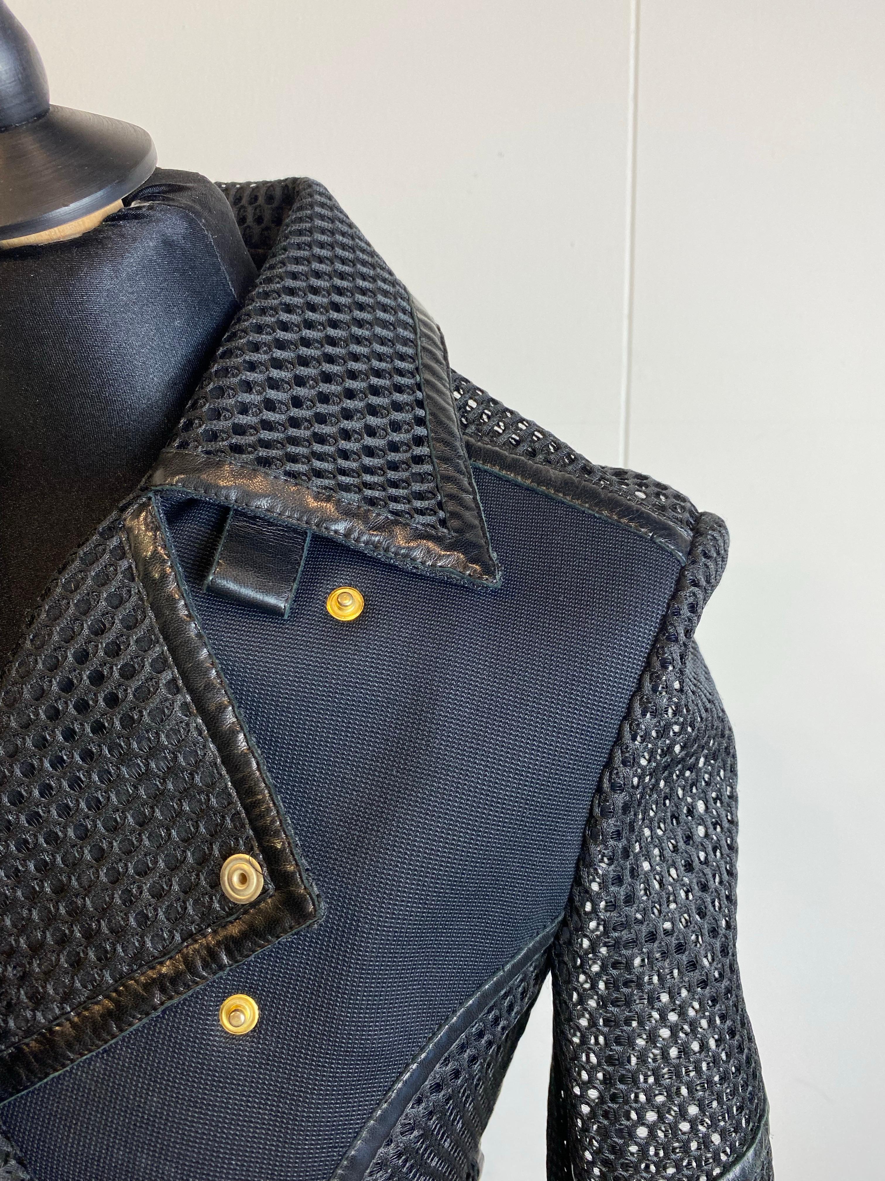 Versace jacket in black fabric with leather details. Perforated parts, closure with clip buttons and some leather parts at the waist and collar. Composition not present. Size 38. Shoulders 40 cm Sleeve 65 cm Bust 40 cm Waist 36 cm Length 50 cm Shows