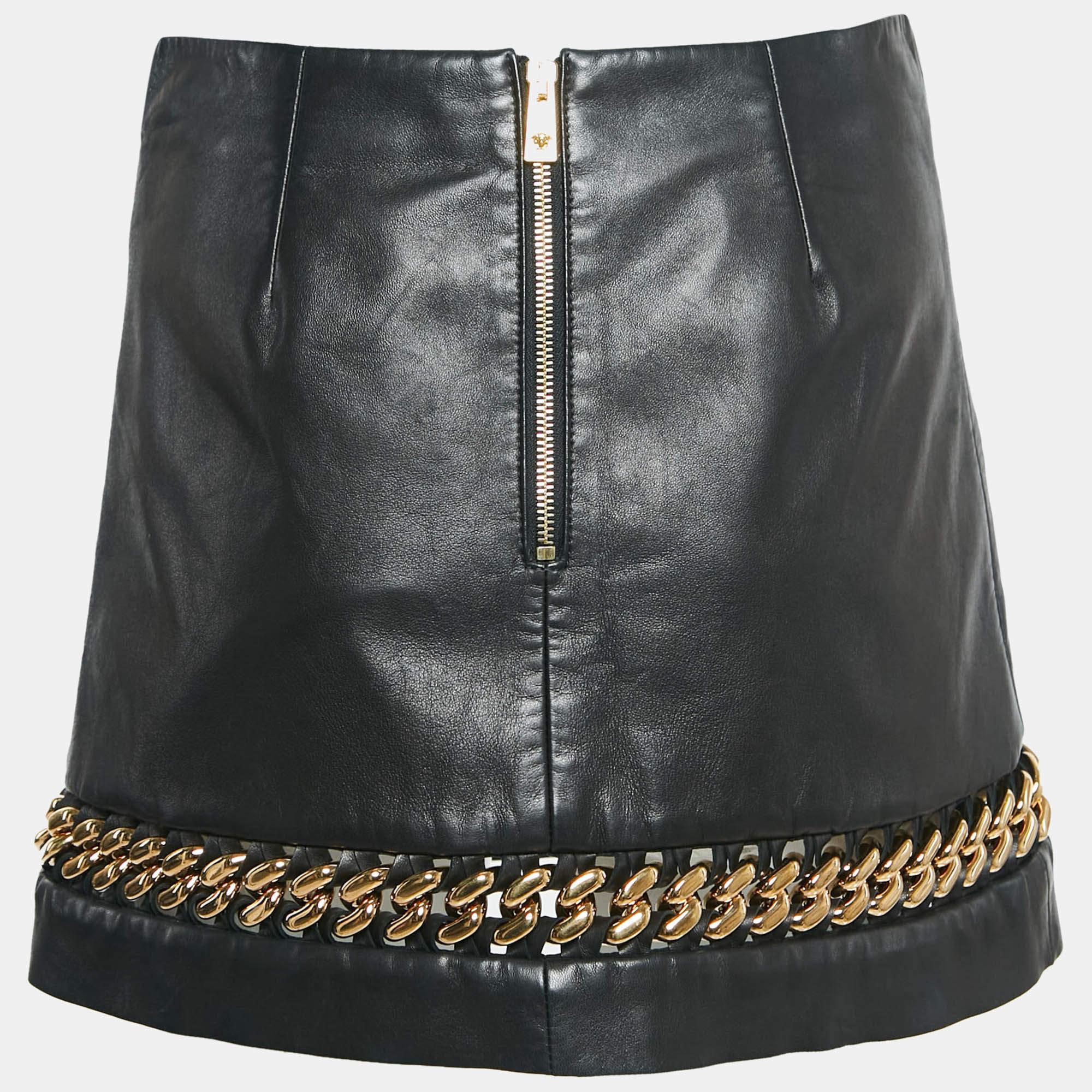 La gonna Versace ha un design elegante e sofisticato, realizzato in pelle nera di alta qualità. Questa minigonna è impreziosita da audaci inserti di catene che aggiungono un tocco di eleganza alla sua silhouette classica. Perfetto per farsi notare,