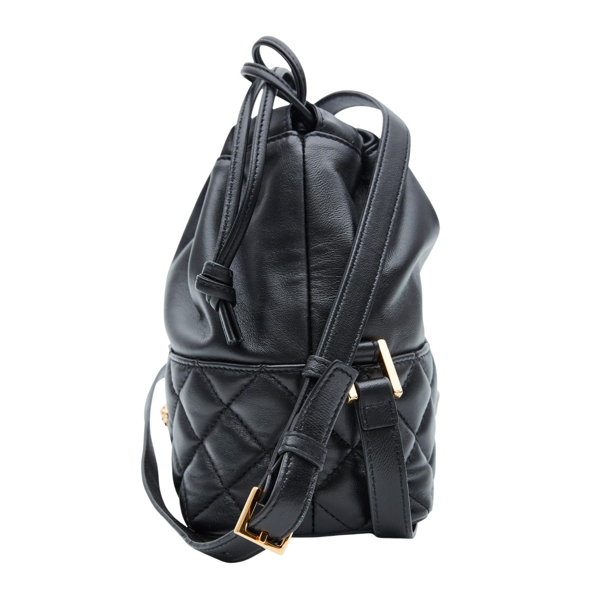 This luxurious bag is crafted of Versace smooth calfskin nappa leather in black. The bag features a leather crossbody strap, gold hardware, quilted leather bottom, smooth leather upper and an open top with drawstring closure. The handbag opens to a