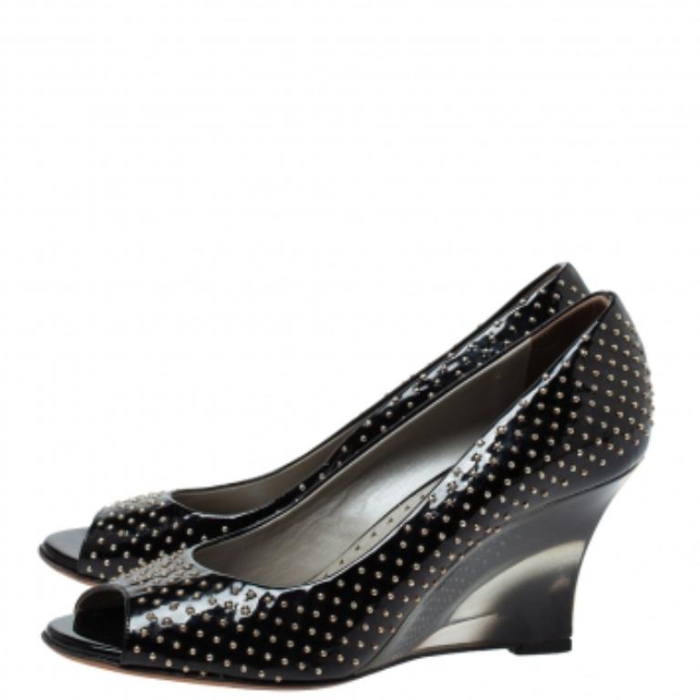 These unique and stunning pumps from the house of Versace will be a valuable addition to your shoe closet. Meticulously crafted in Italy, they are made from glossy black patent leather and adorned with studs all over. They feature a peep-toe design