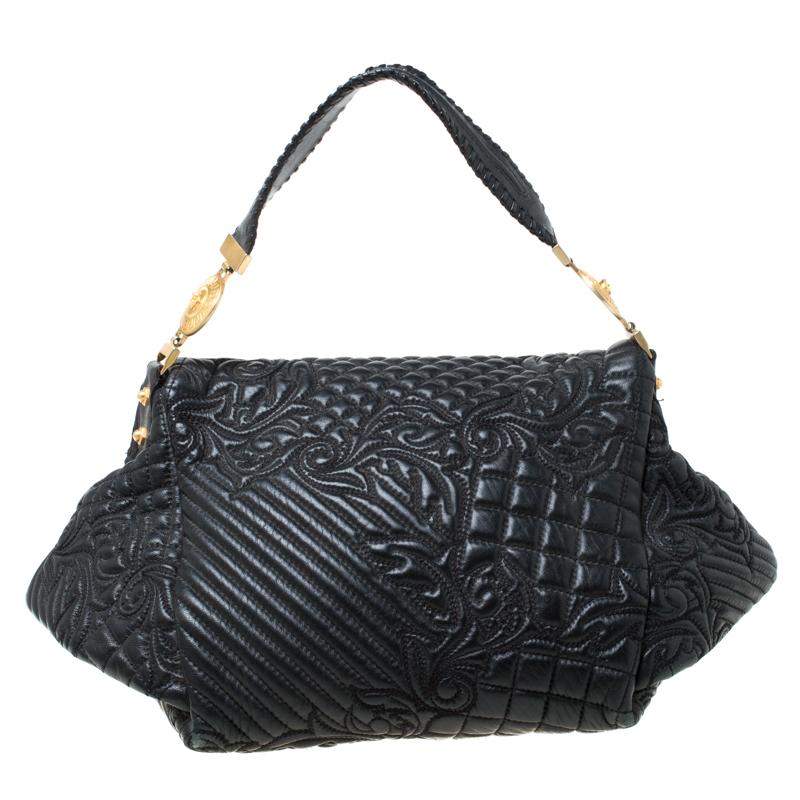 This Versace handbag is meticulously crafted from quilted leather. The Barocco bag delights not only with its appeal but structure as well. It is held by a single handle, adorned with a lovely embroidery all over and equipped with a spacious satin
