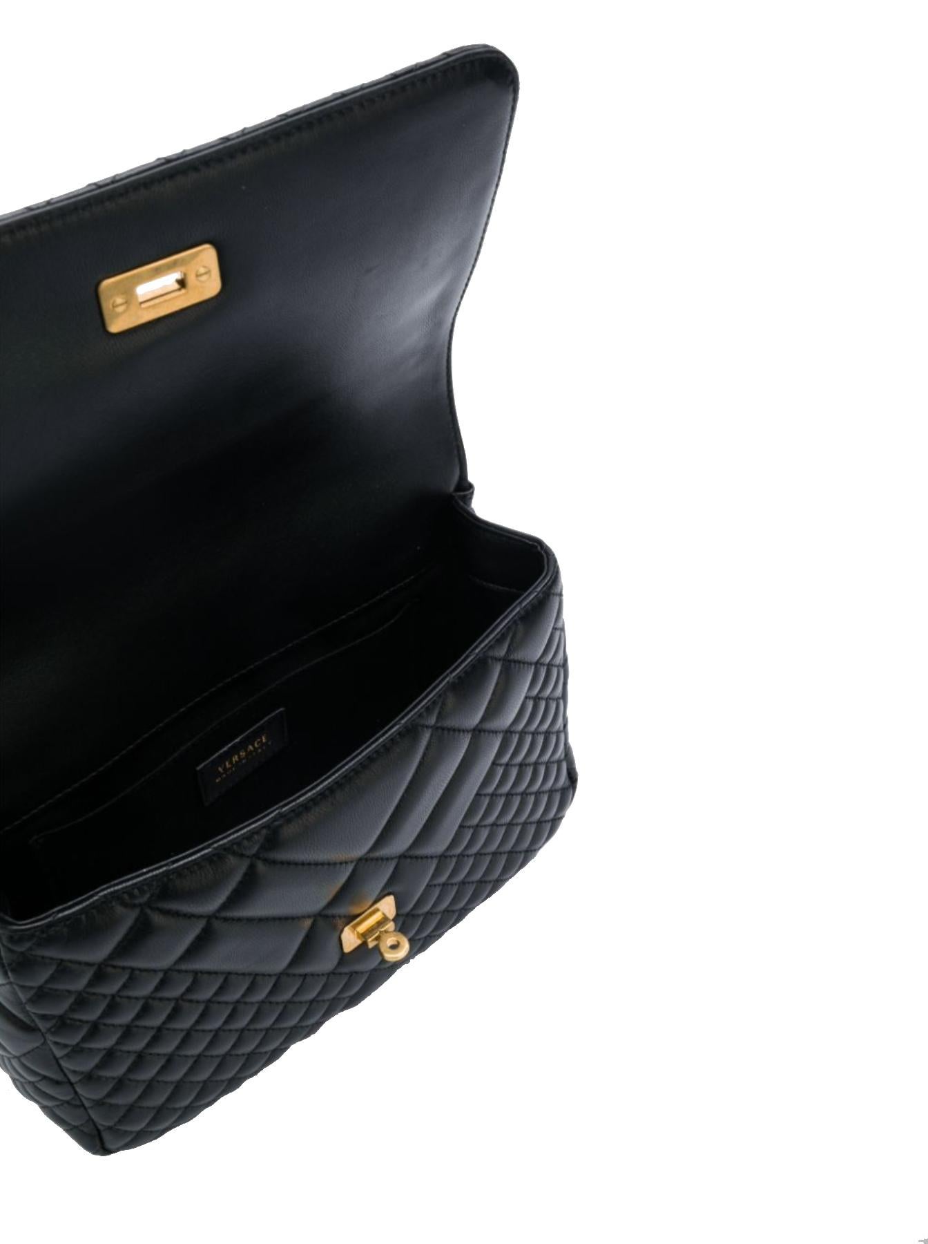 Ce sac à bandoulière Versace Medium Quilted Icon présente un corps en cuir noir matelassé:: une fermeture à rabat:: une bandoulière en chaîne tressée de couleur or et des poches intérieures. Ce sac Icon est immédiatement reconnaissable grâce aux