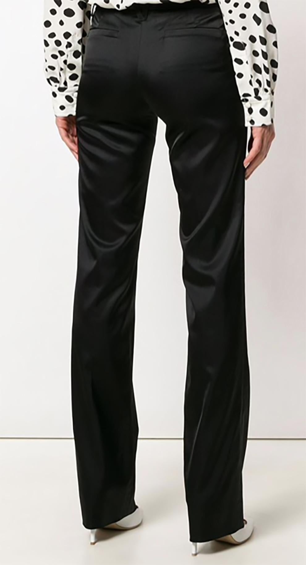 Versace black bootcut satin trousers featuring a low rise, a waistband with belt loops, a concealed front fastening, front welt pockets, rear welt pockets, a slim fit and a regular length. 
In excellent condition. Made in Italy. 
Estimated size
