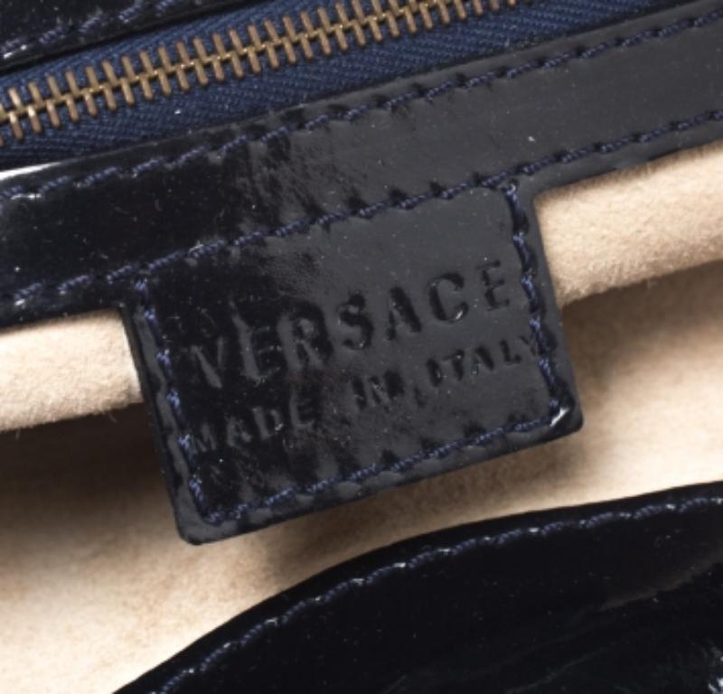 Questa elegante borsa a tracolla di Versace è elegante e unica nel suo genere. Realizzata in Italia, è in vernice lucida e presenta una bella tonalità di nero. È sorretto da due manici a catena e l'esterno è impreziosito da dettagli in cucitura e da