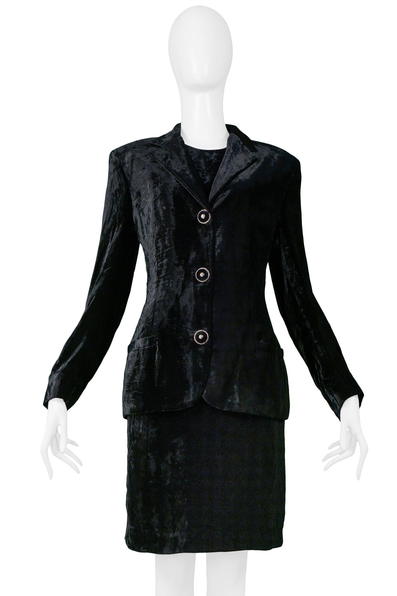 Resurrection Vintage è lieta di presentare un ensemble di giacca e gonna in velluto nero di Gianni Versace, composto da un blazer in velluto nero con grandi bottoni neri e argentati e un abito al ginocchio senza maniche in velluto nero. 

Versace