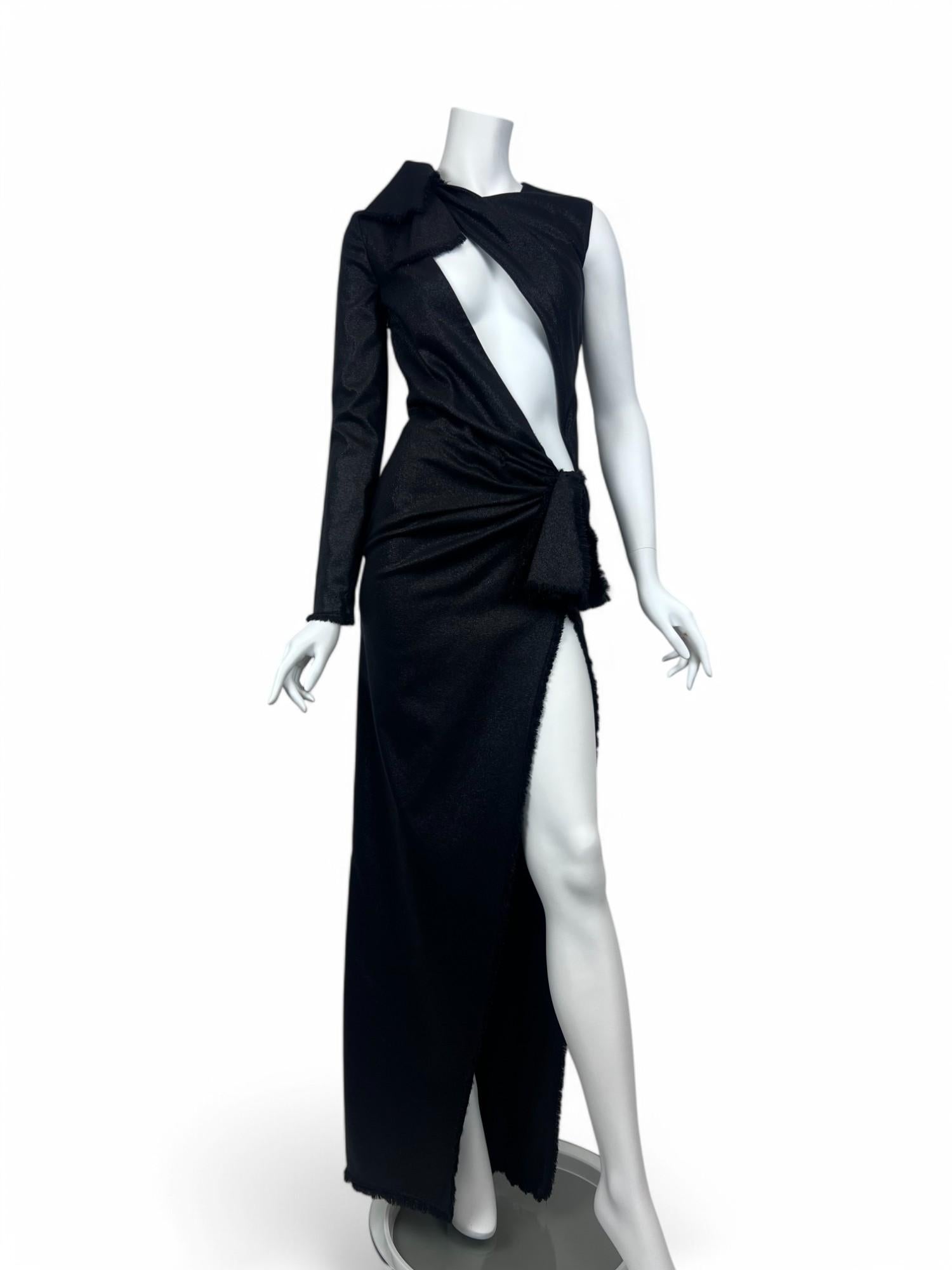 Elegante, sofisticato e innegabilmente audace, questo abito Cut-Out in lana nera di Versace incarna la fusione di sartoria e sensualità tipica della maison. Realizzato in lussuosa lana nera, l'abito presenta una silhouette aderente che si drappeggia