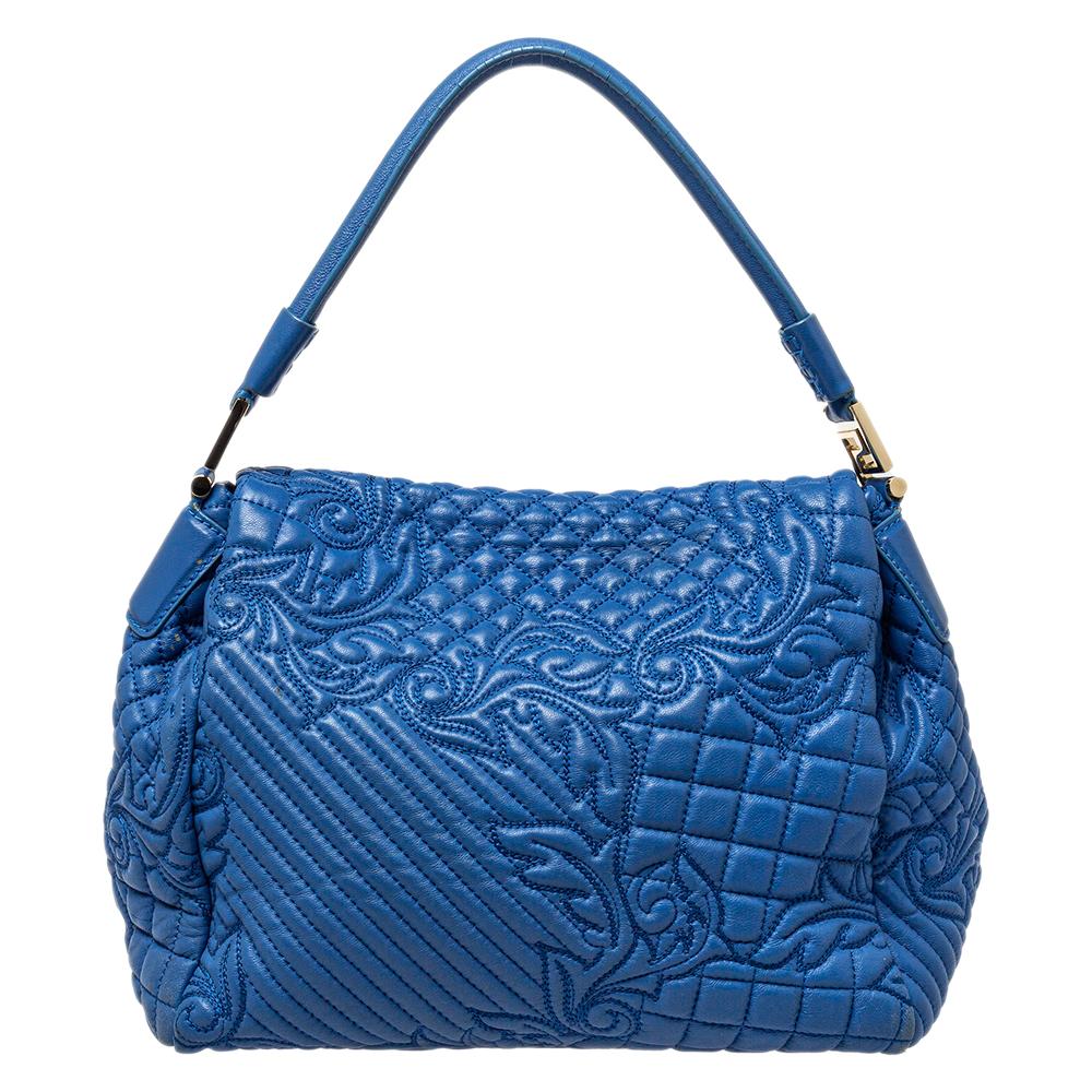 Royal and chic, this Versace Talia Vanitas shoulder bag is an example of the label's rich heritage. It is designed in an exquisite blue embossed leather with tonal stitch detailing on it. It features a flap silhouette and comes decorated with