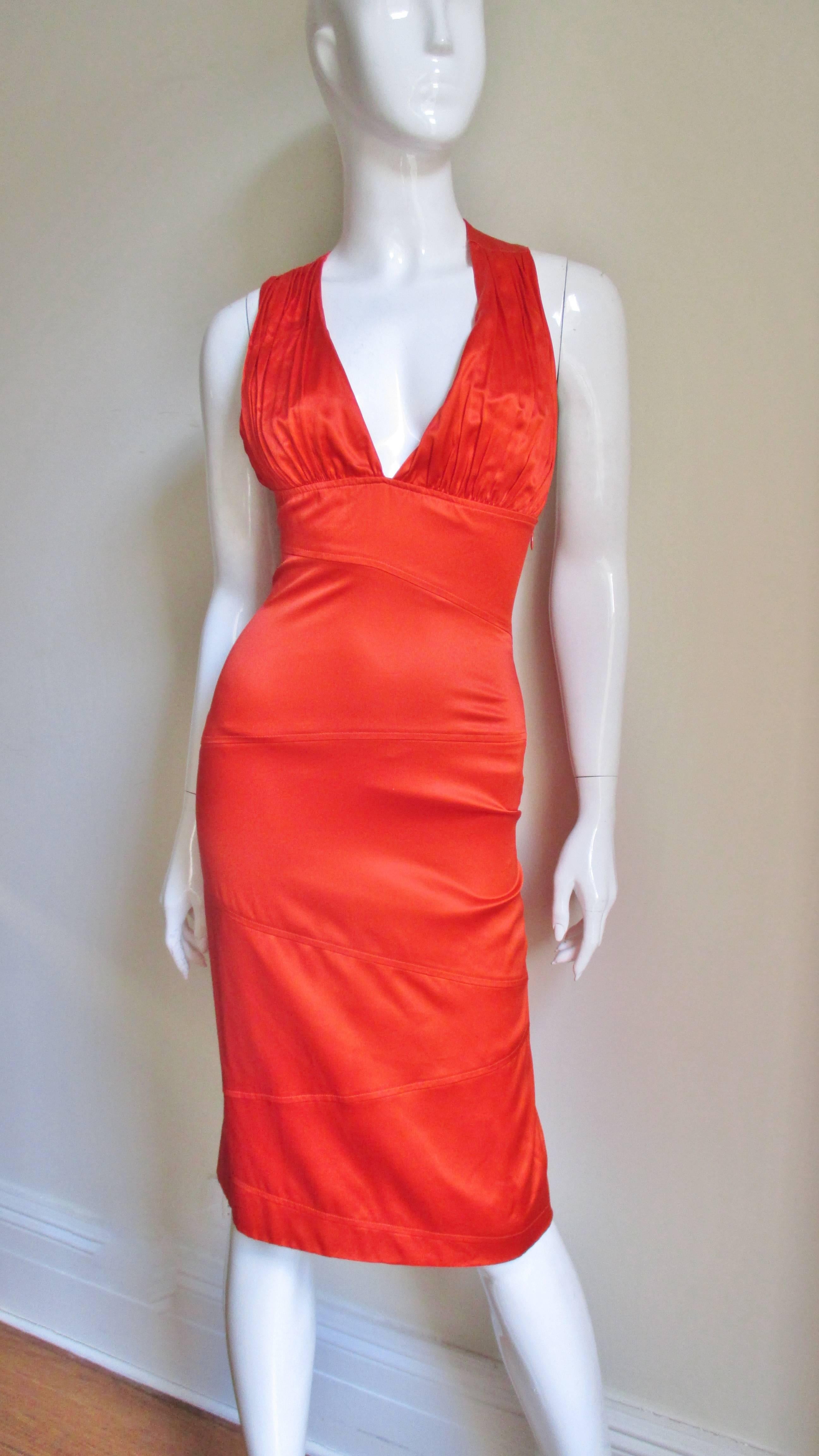 A gorgeous orange fine stretch silk dress from Versace.  It has a plunging front neckline attached to a fitted band around the midriff.  The straight skirt portion is pieced together in horizontal angle seams front and back.  The back is absolutely