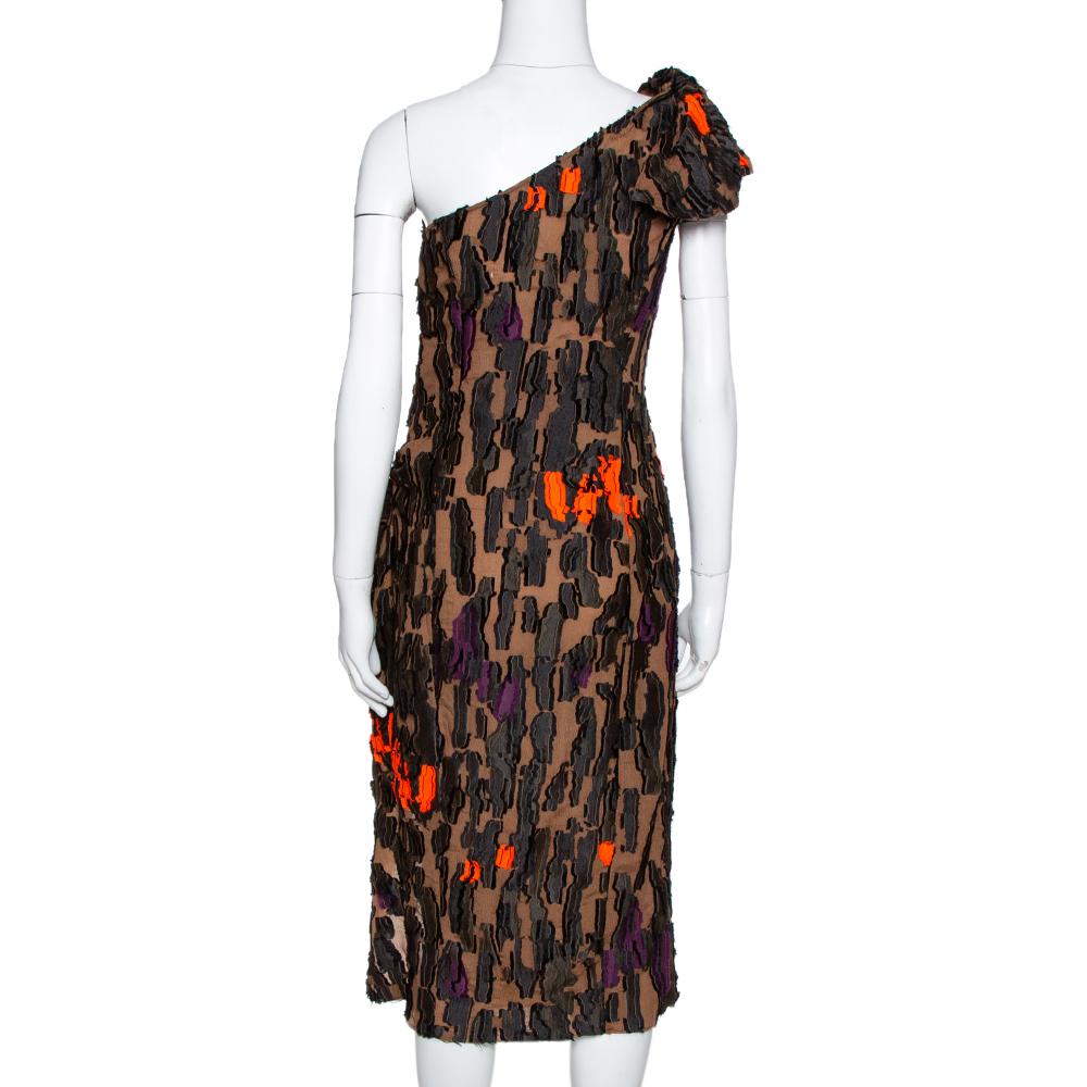 This Fil Coupé dress from the Versace's Summer Spring 2016 collection stays true to the label's creative DNA. This brown camouflage creation is made from jacquard fabric. The one-shoulder dress has distinct touches of orange on it. When paired with