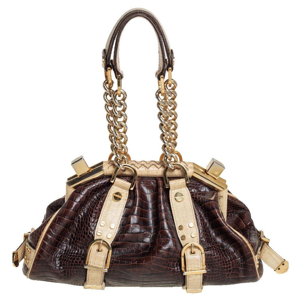 The Madonna satchel from Versace is made from croc-embossed leather. It comes with two chain and leather handles, gold-tone hardware, and the signature Medusa logo detailing on the front. It is lined with satin on the insides and will easily hold