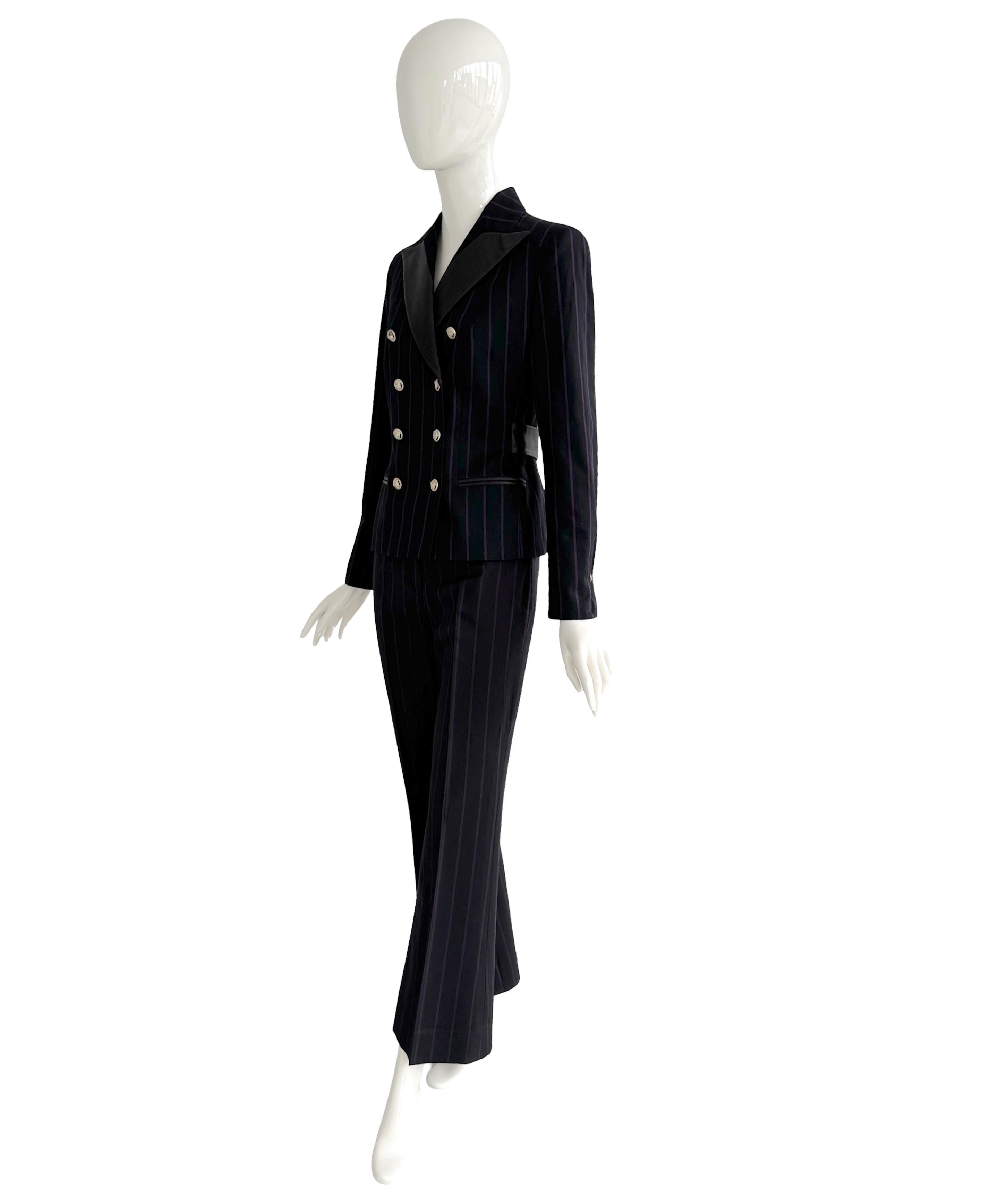 Raro traje temprano de Donatella Versace para Versace Otoño-Invierno 1998 en un tejido de lana y seda a rayas de color morado oscuro con un toque de elasticidad. 
(57% lana - 40% seda - 2% elastán) 
La chaqueta de doble botonadura tiene solapas de