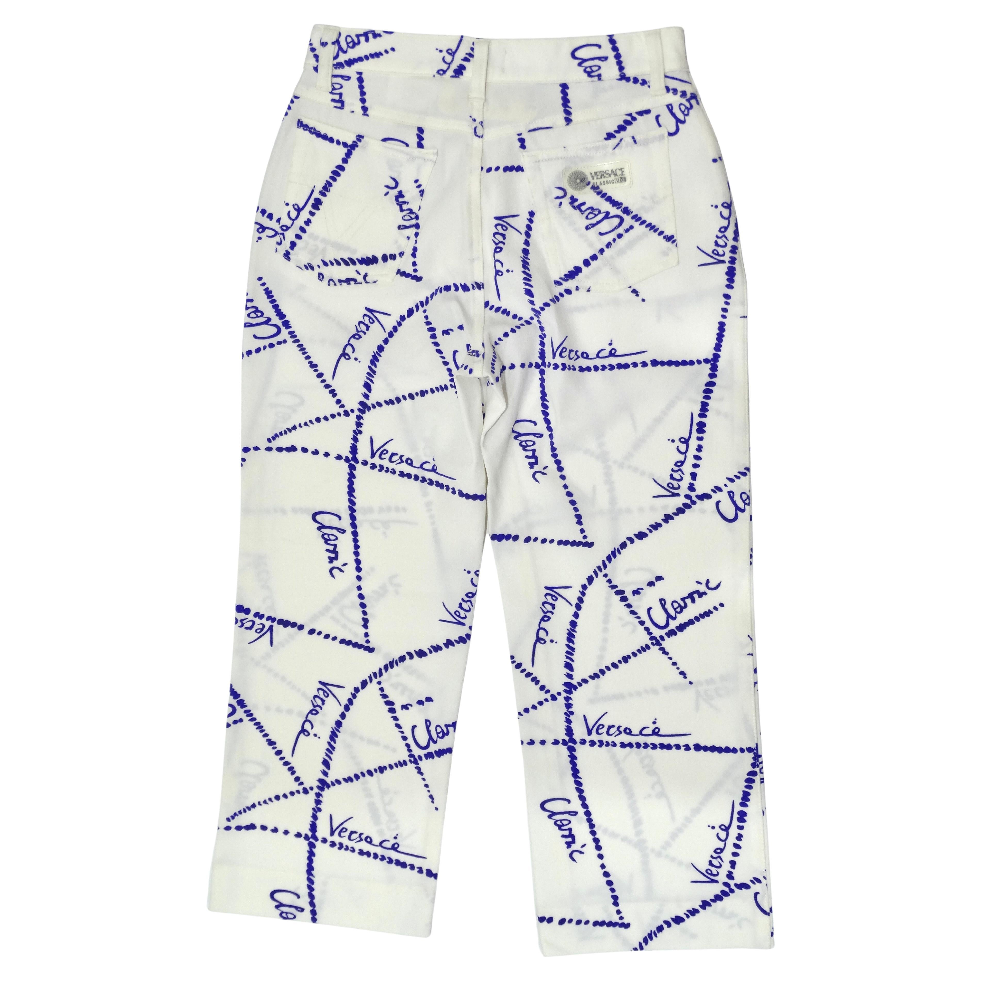 These are an ultra-rare pair of Versace trousers with a paired-back pattern and cropped length. The pattern depicts blue dotted lines and cursive 'versace' throughout. Features button closure, strechy fabric, straight leg, and an ultra-high rise.