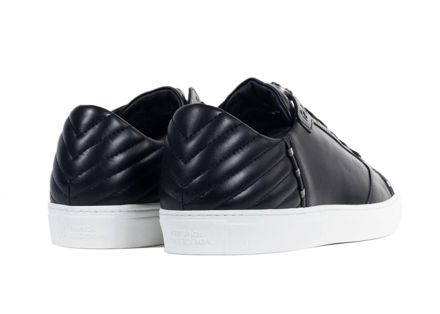 Leave an impact in your Low Top Black Versace Collection Sneakers. These leather sneakers feature modern metal rivets, an artistically chevron stitched heel, and signature 3-D Logo Emblem on the Tongue. Pair these sneakers with black leather pants