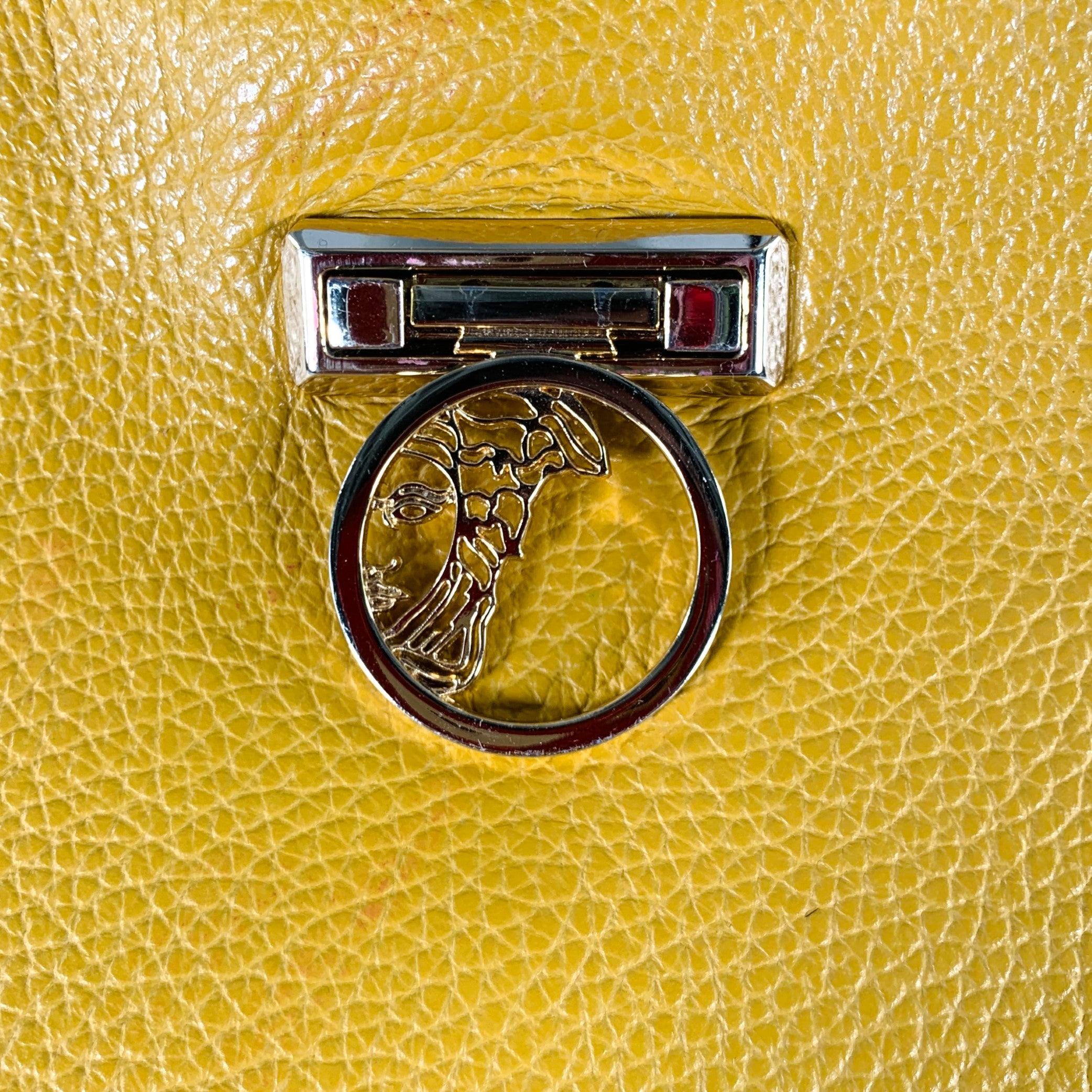 VERSACE COLLECTION handbag in a mustard yellow pebble grain leather featuring gold tone chain shoulder strap, spacious interior, and gold tone metal closure with Medusa head detail. Made in Italy.Very Good Pre-Owned Condition. 

Marked:   876 561