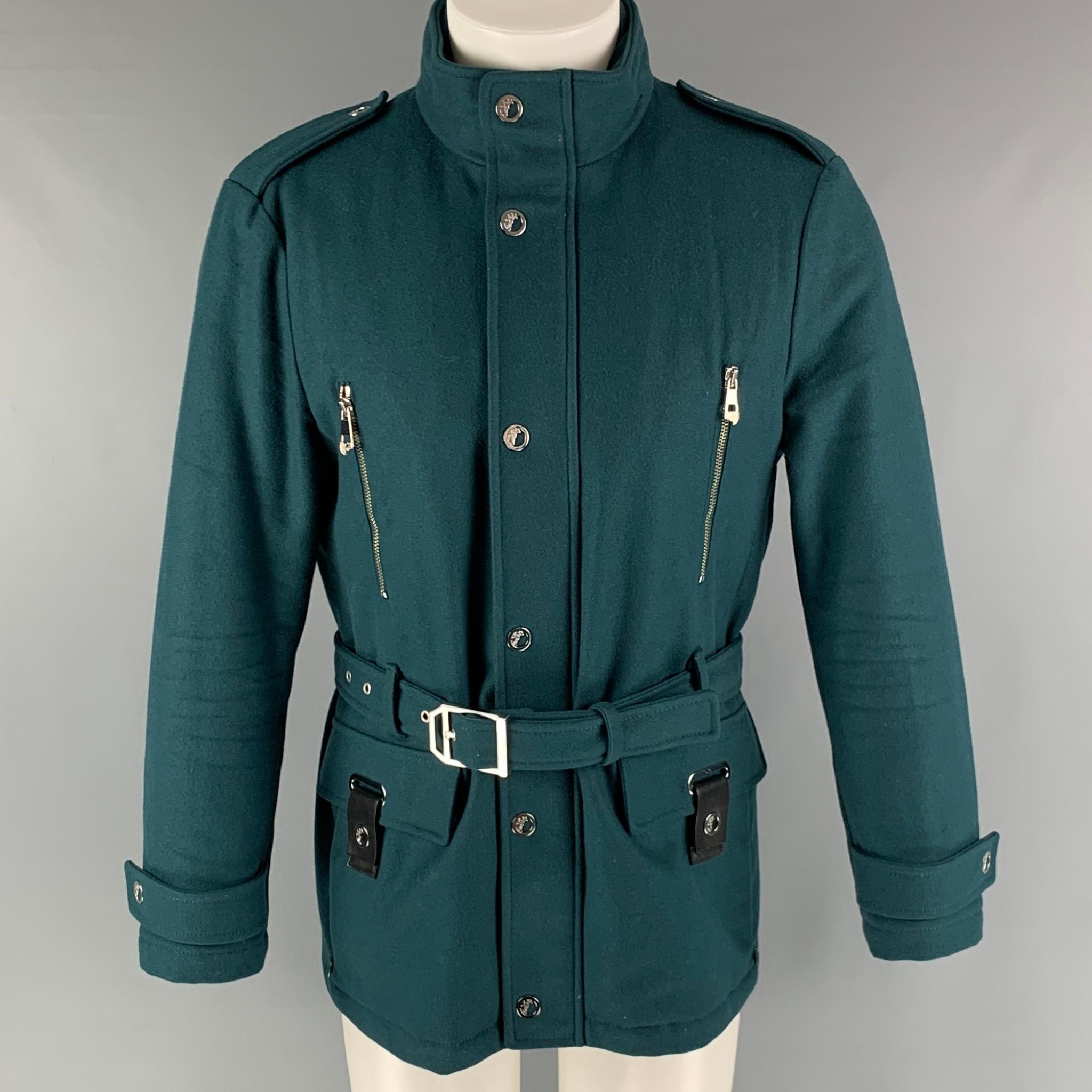 VERSACE COLLECTION jacket comes in a green wool blend woven material featuring a belted style, flap pockets, epaulets, hidden hood, silver medusa hardware, and a zip up and snap button closure.

Excellent Pre-Owned Condition.
Marked: IT