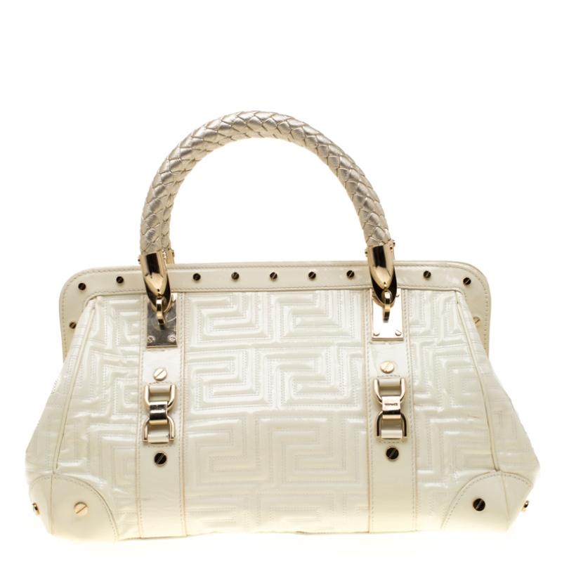 This eye-catching Versace Snap Out Of it satchel is sure to make heads turn. Crafted from cream quilted leather, the bag is accented with a Gianni Versace Couture plate and gold-tone studded hardware. It features dual top braided handles and a top