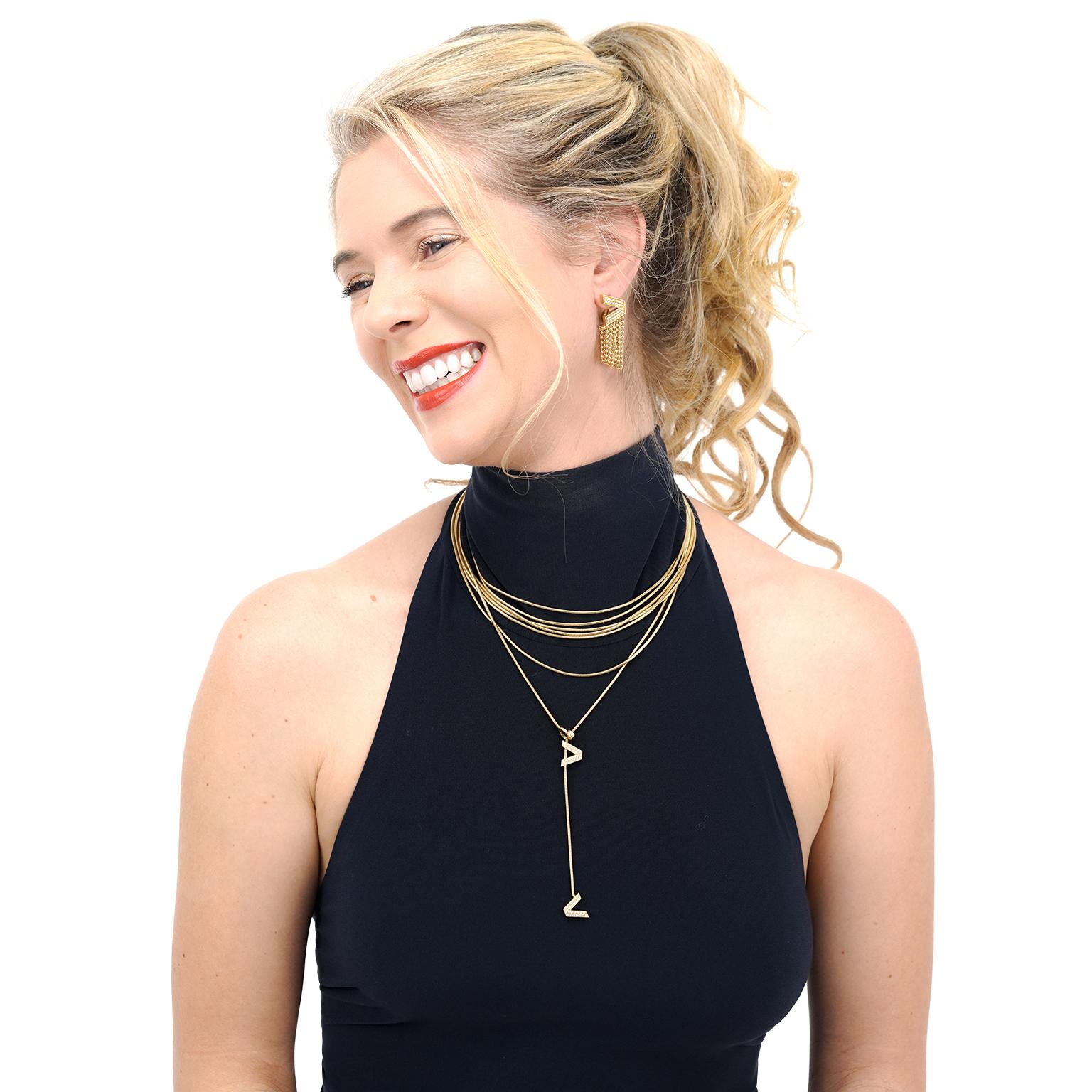 Circa 1990s, 18k, by Versace, Italy. These fabulous fine jewelry earrings by Versace are a fashionista's dream…  a rare find!  The designer's V is set with .64 carats of fine white diamonds are festooned with playful strands of gold bead chain for a