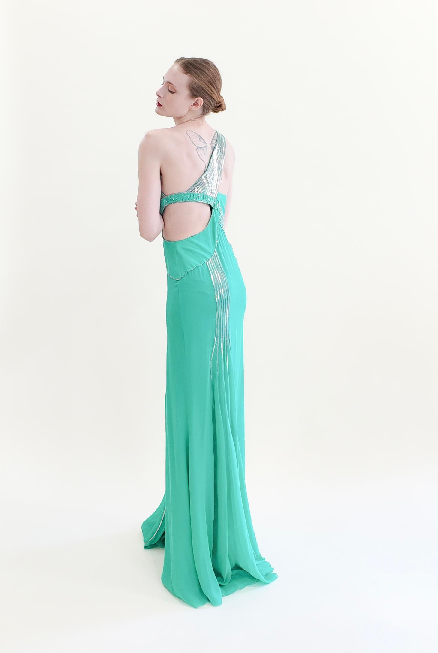 Concediti una fantasia di moda con l'abito monospalla Versace Primavera 2010 Aqua con borchie metalliche. Questo abito da sogno color acqua presenta una seducente scollatura asimmetrica e un ritaglio in vita per un tocco sensuale. Il design a