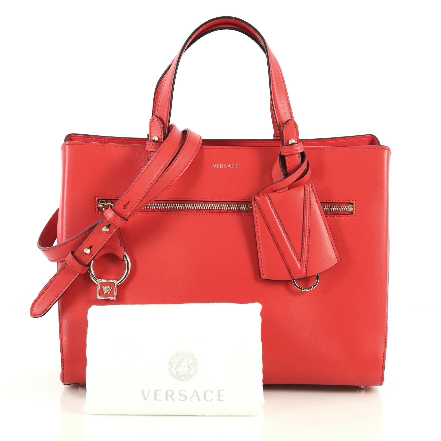 This Versace DV One Tote Leather Medium, crafted in red leather, features dual leather handles, exterior zip pocket and gold-tone hardware. It opens to a red leather interior with a center zip compartment. 

Estimated Retail Price: $3,075
Condition: